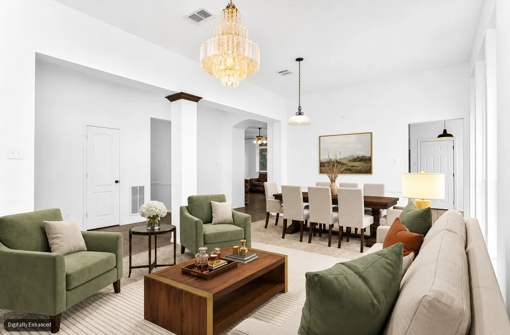 Spacious open-concept interior featuring light walls, a crystal chandelier, and a decorative column