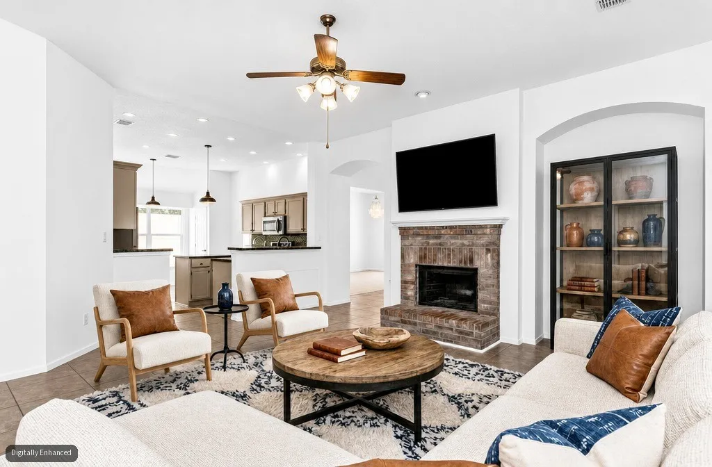 Brick-faced fireplace with a mantel, ceiling fan with integrated lighting, recessed lighting, arched entryway, and tile flooring