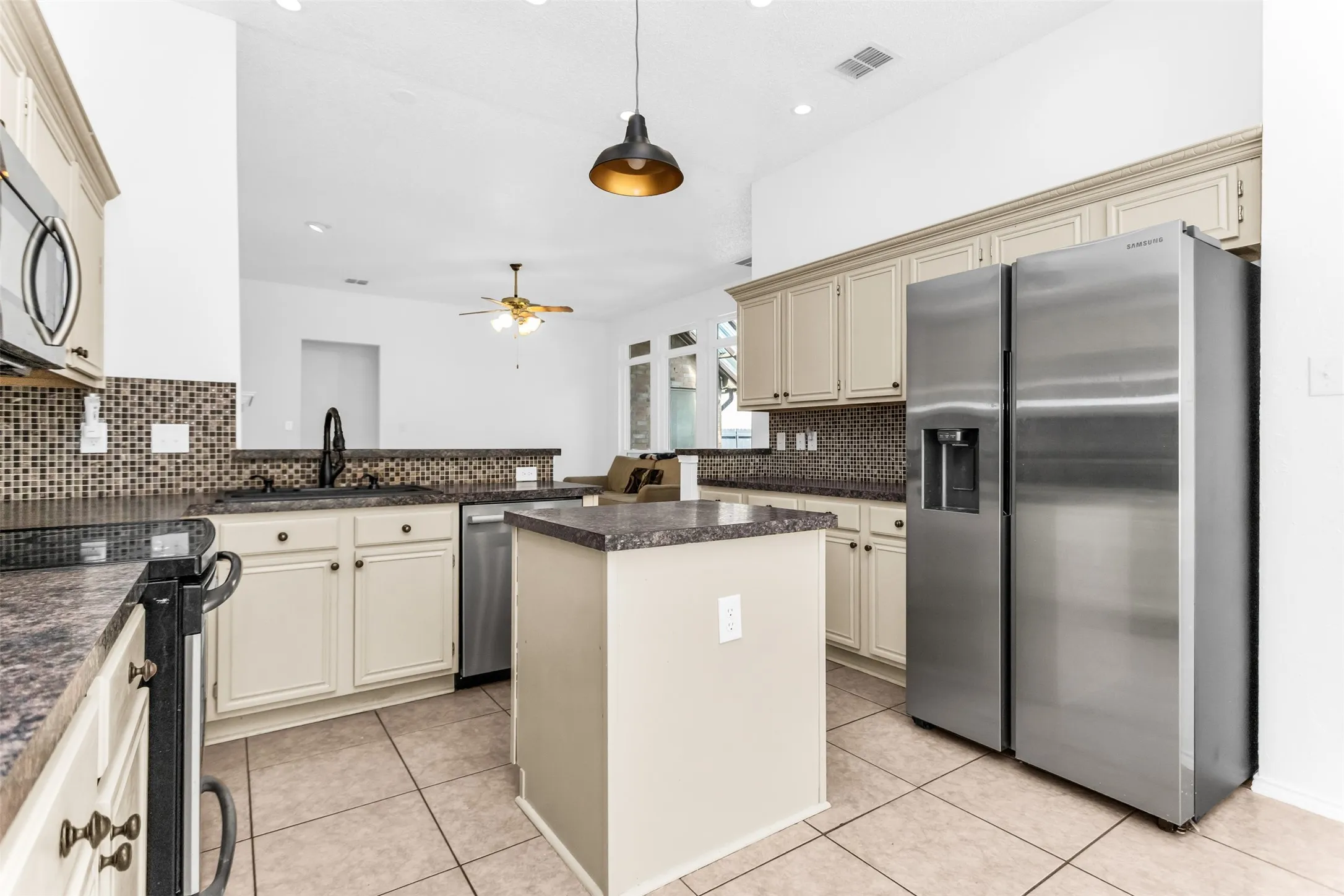 Cream-painted cabinetry with dark hardware, a mosaic tile backsplash, and a black countertop