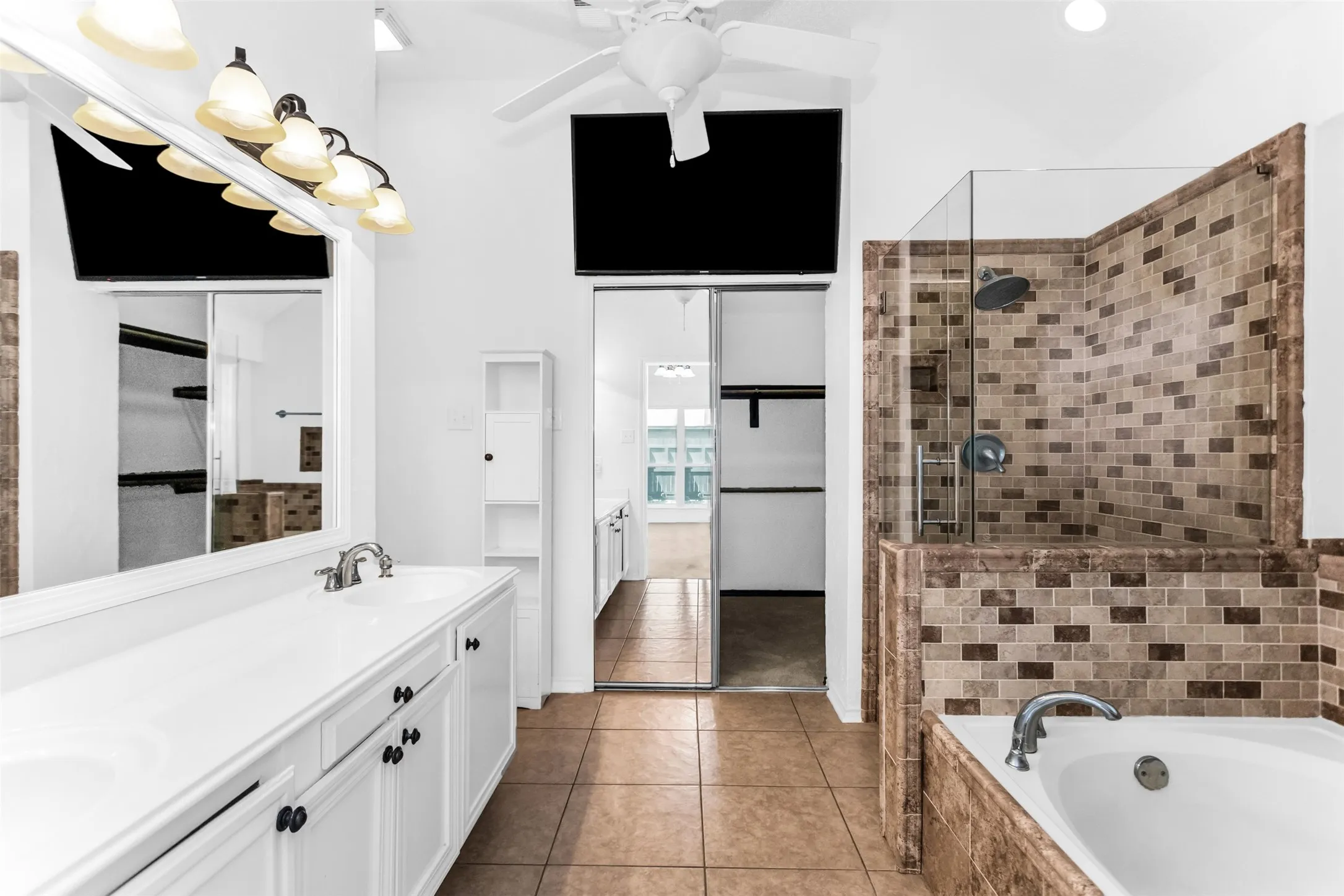 Dual vanity with white cabinetry, tile flooring, glass-enclosed shower with tile surround, and a built-in soaking tub with tile​​‌​​​​‌​​‌‌​‌‌​​​‌‌​‌​‌​‌​​​‌​​ surround