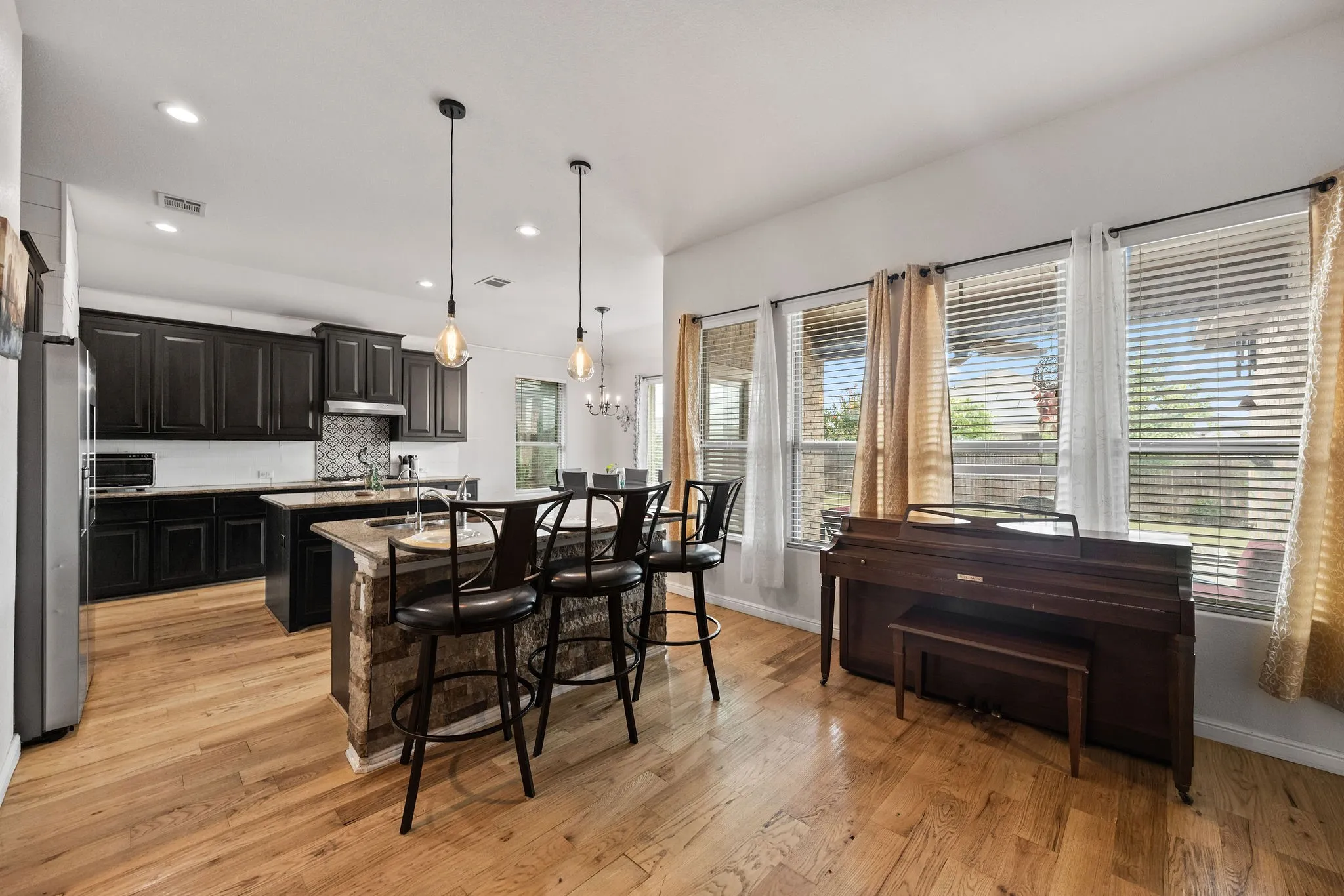 Open-concept kitchen featuring dark wood cabinetry, white countertops, and a patterned tile backsplash