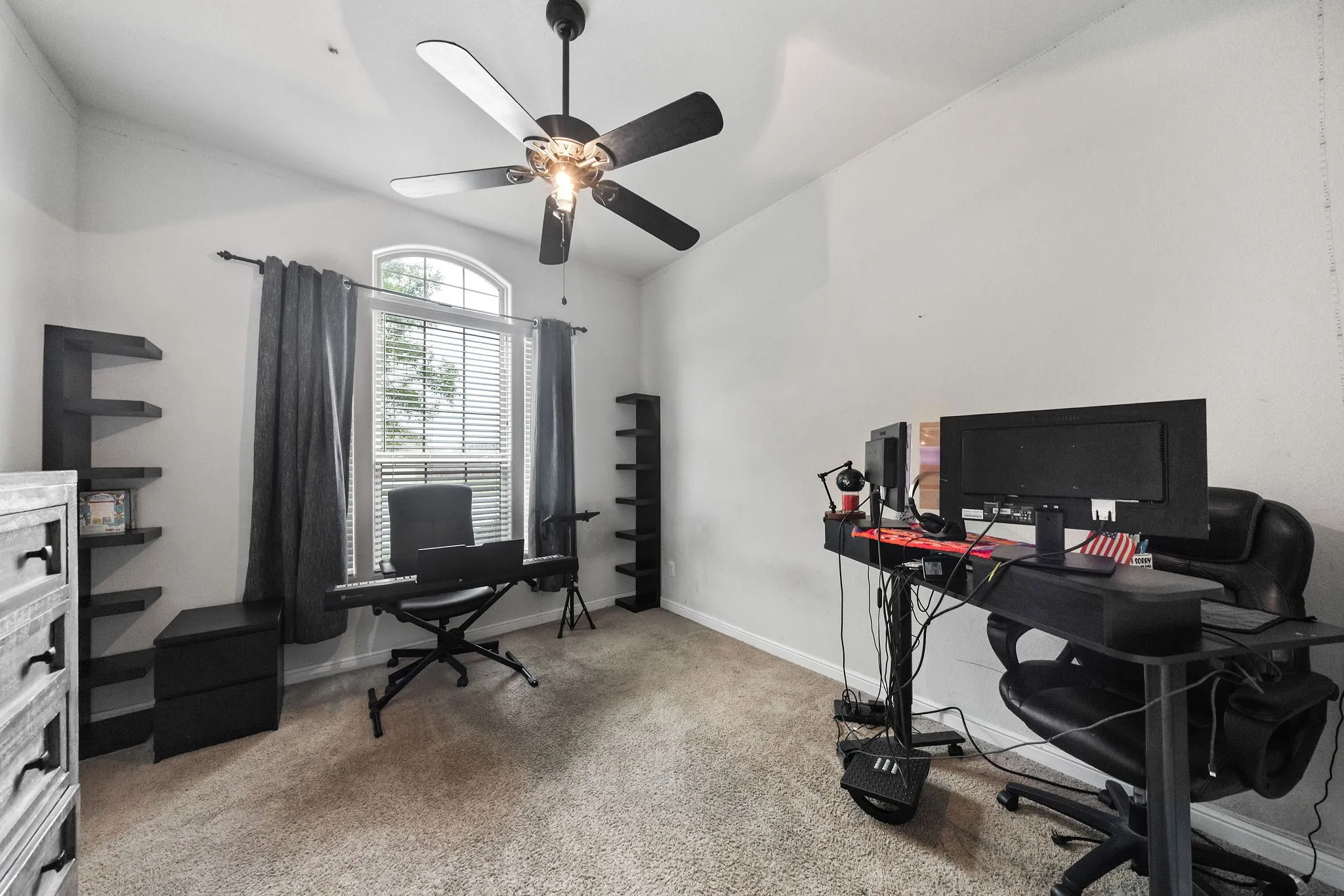 Spacious room featuring vaulted ceilings, an arched window with blinds, and a ceiling fan with integrated lighting