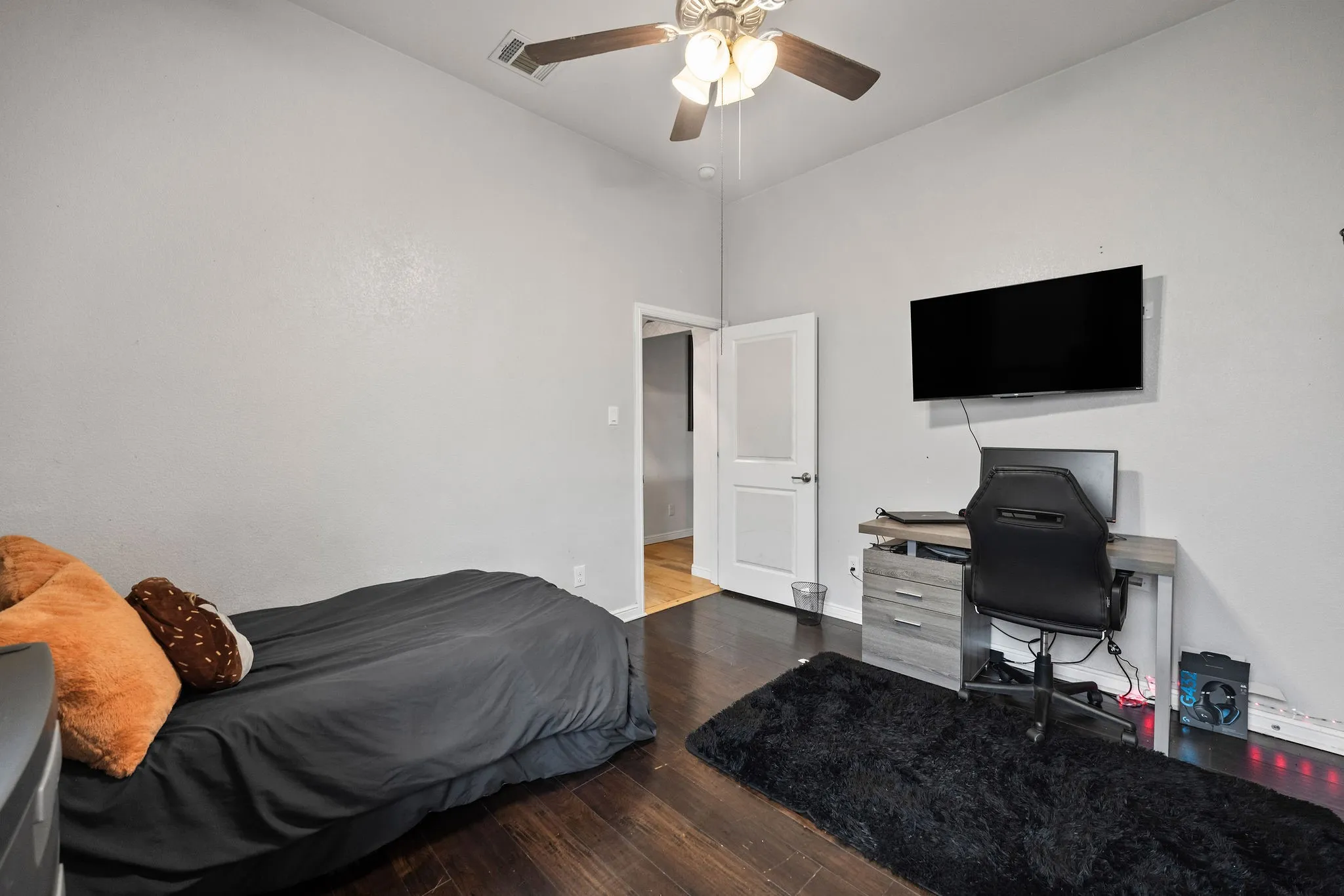 Room featuring wood-finish flooring, a white interior door with frosted glass panels, and a ceiling fan with integrated lighting