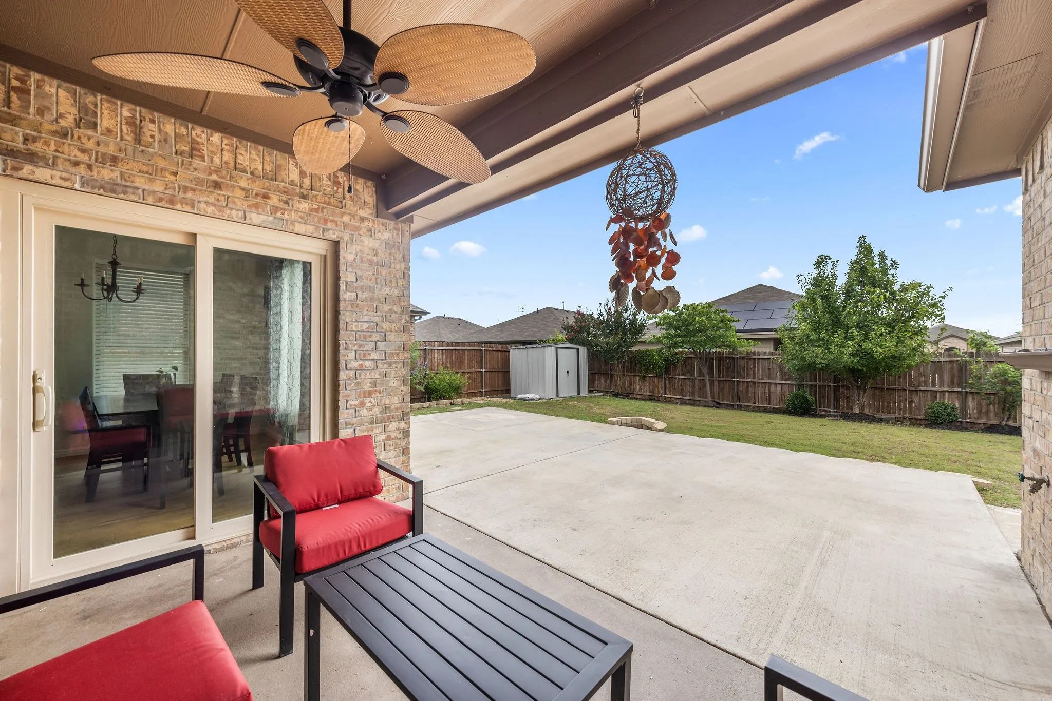 Covered patio with a ceiling fan, brick exterior, and concrete flooring