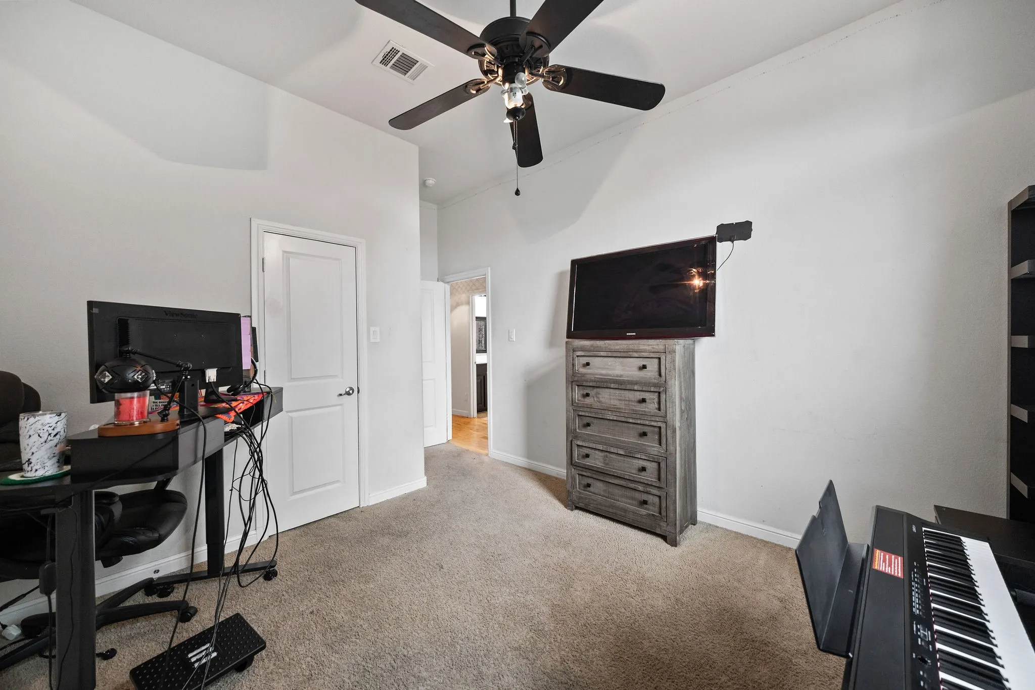 Carpeted room featuring a ceiling fan with light fixture and light-toned walls