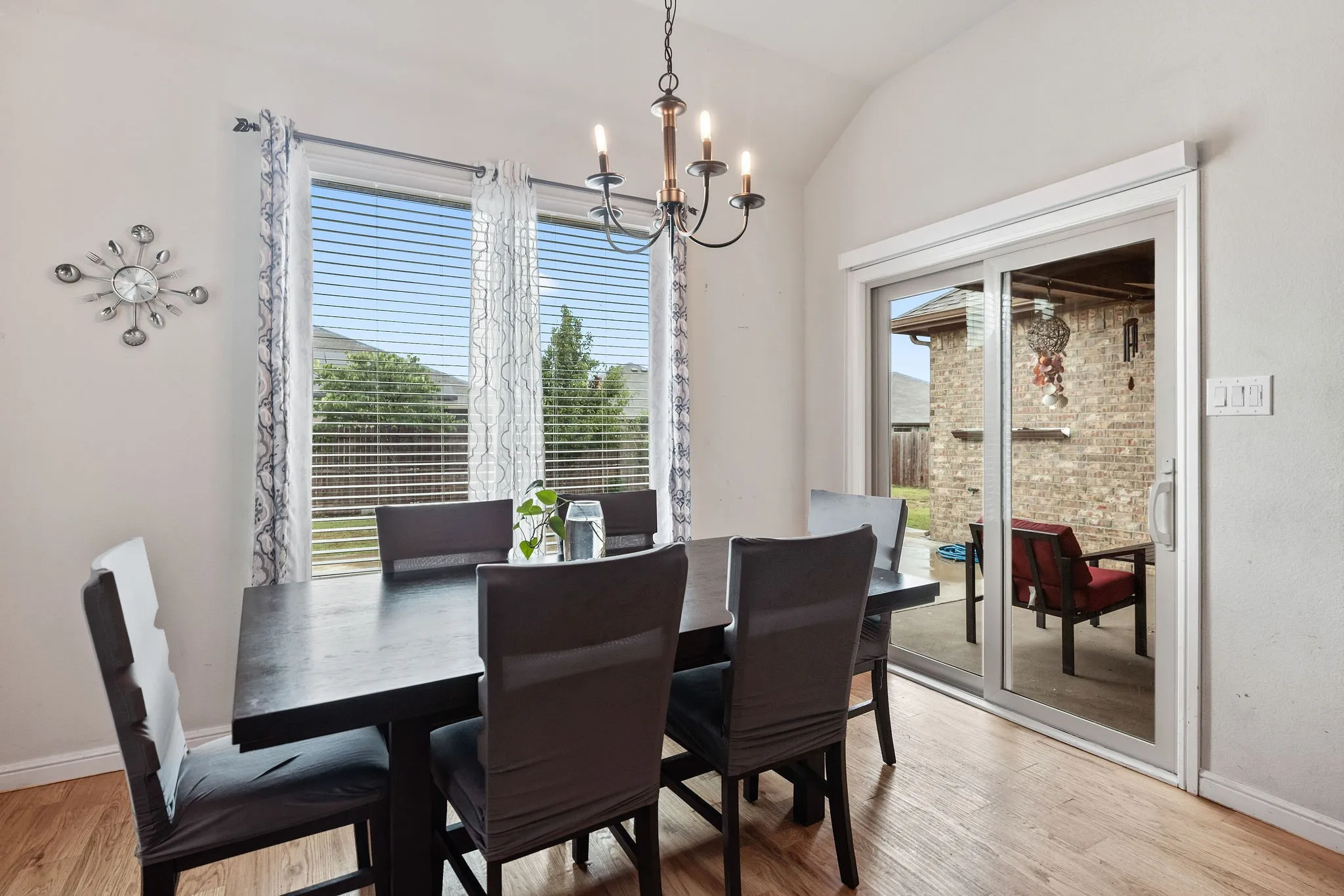 Dining area featuring wood-finish flooring, vaulted ceilings, and a bronze chandelier