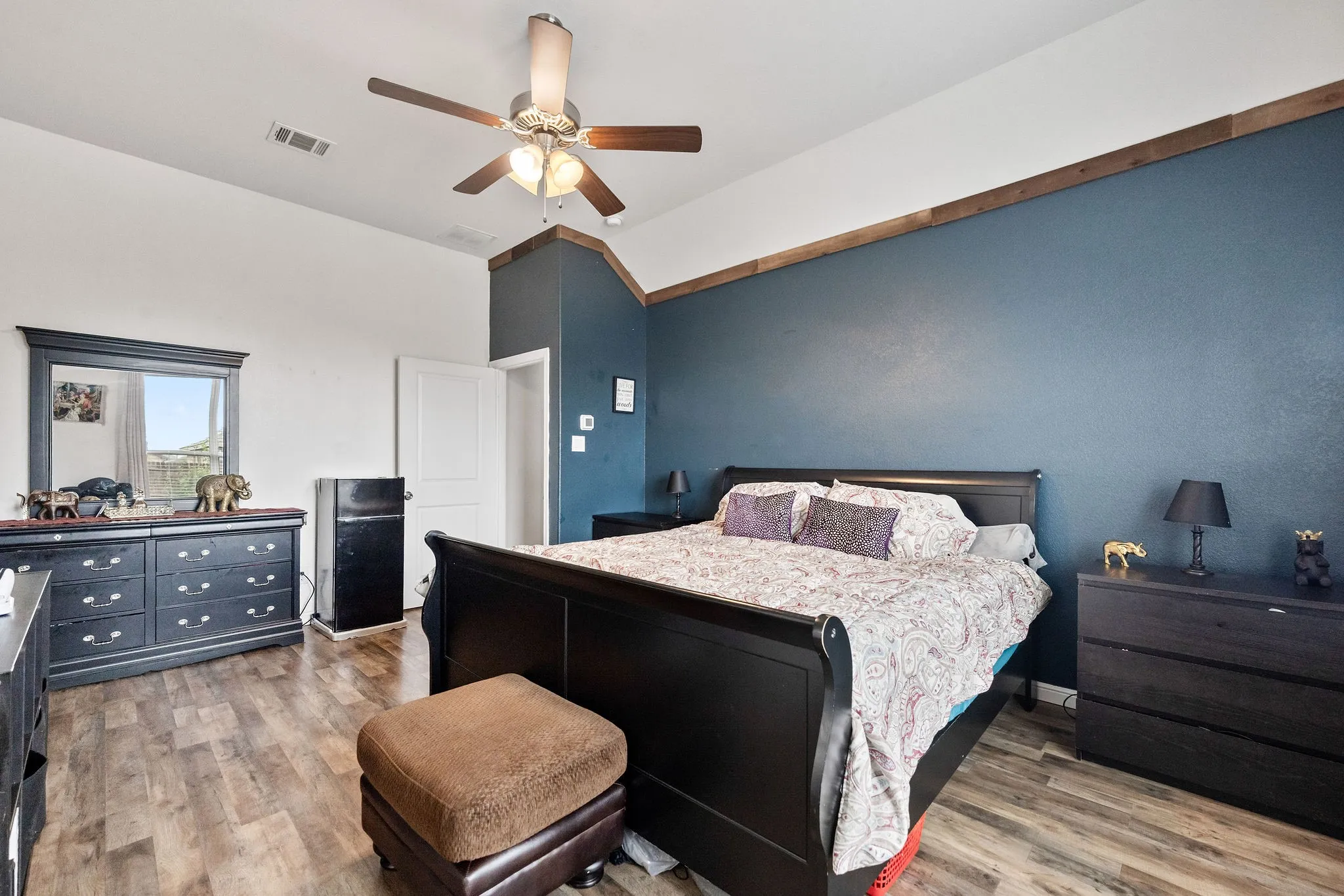 Spacious room featuring wood-finish flooring, a vaulted ceiling, and a ceiling fan with integrated lighting