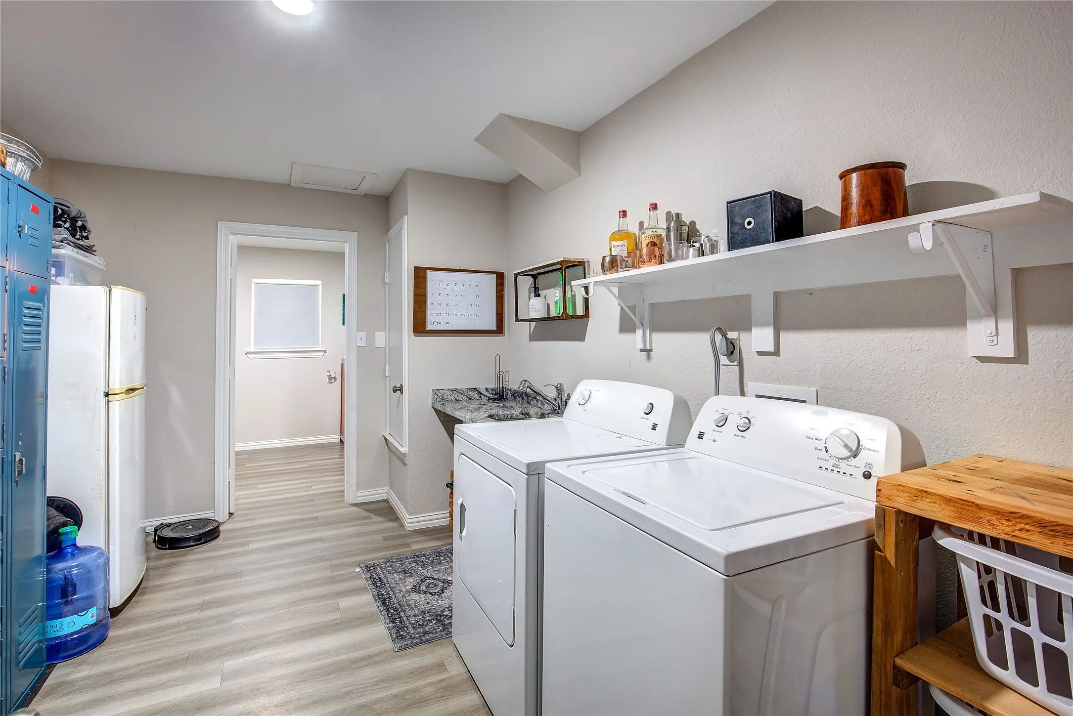 Washroom with washing machine and clothes dryer, attic access, and light wood-style floors