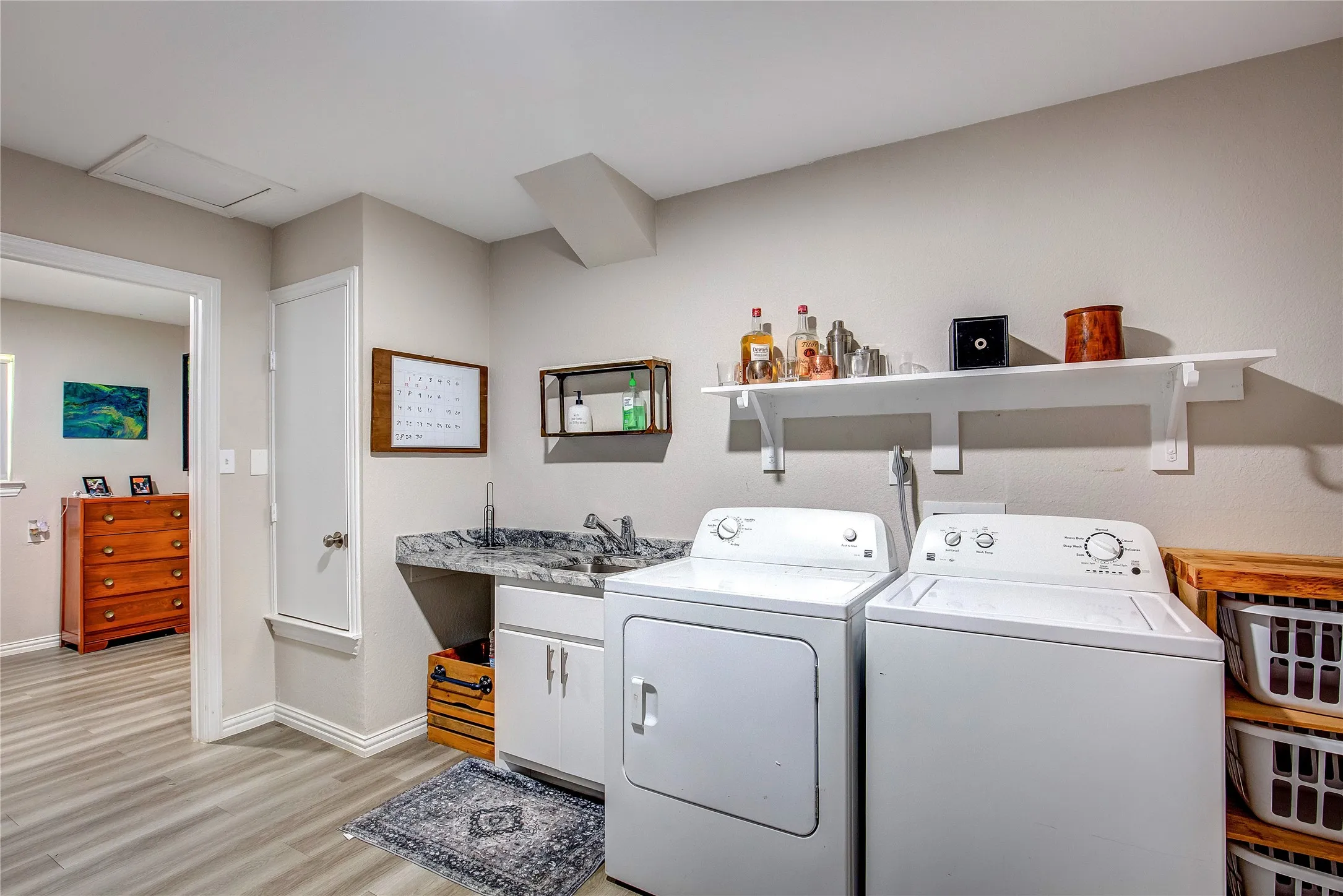 Laundry area featuring washer and dryer, light wood-style flooring, cabinet space, and attic access
