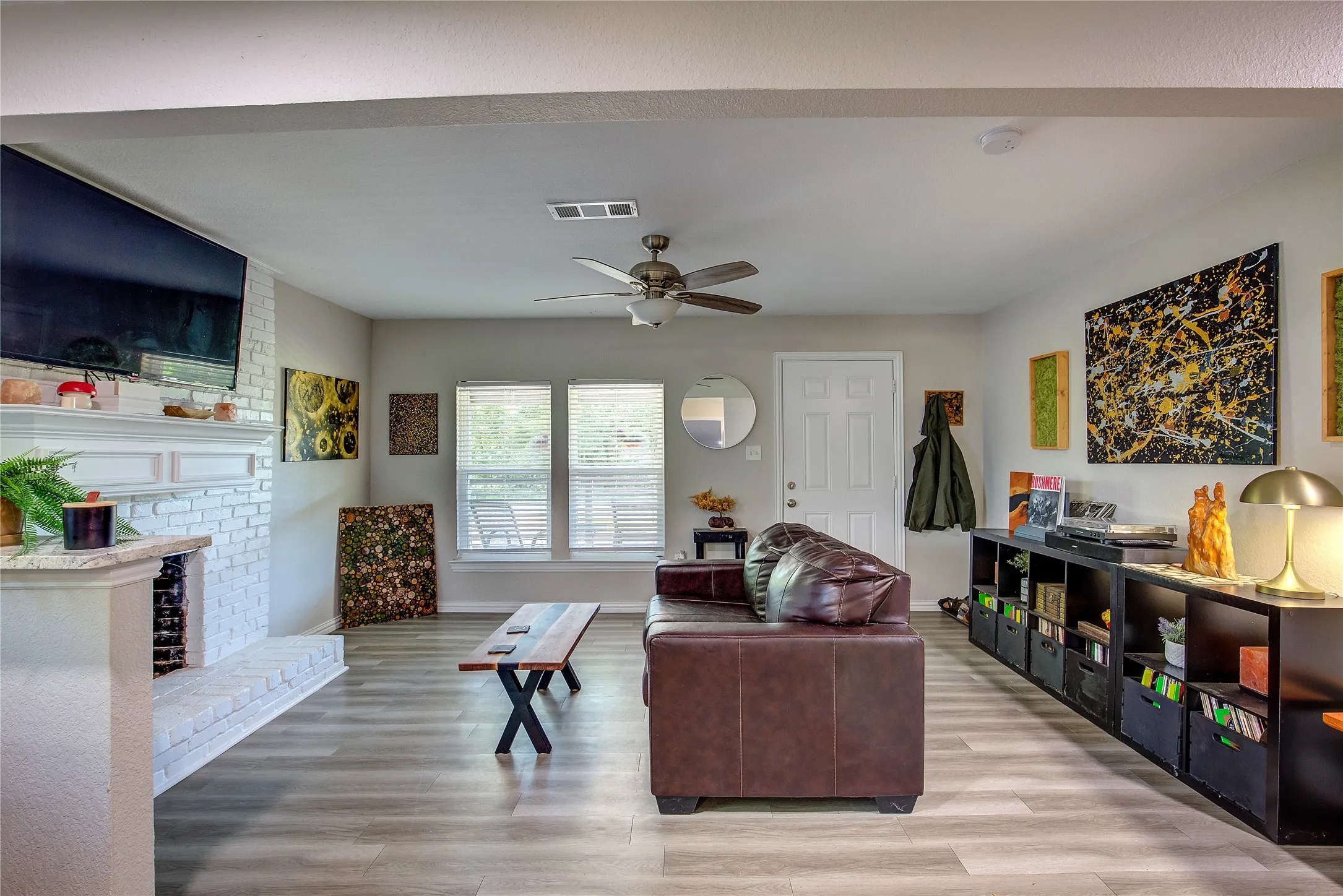 Living area featuring a fireplace, a ceiling fan, and light wood-type flooring
