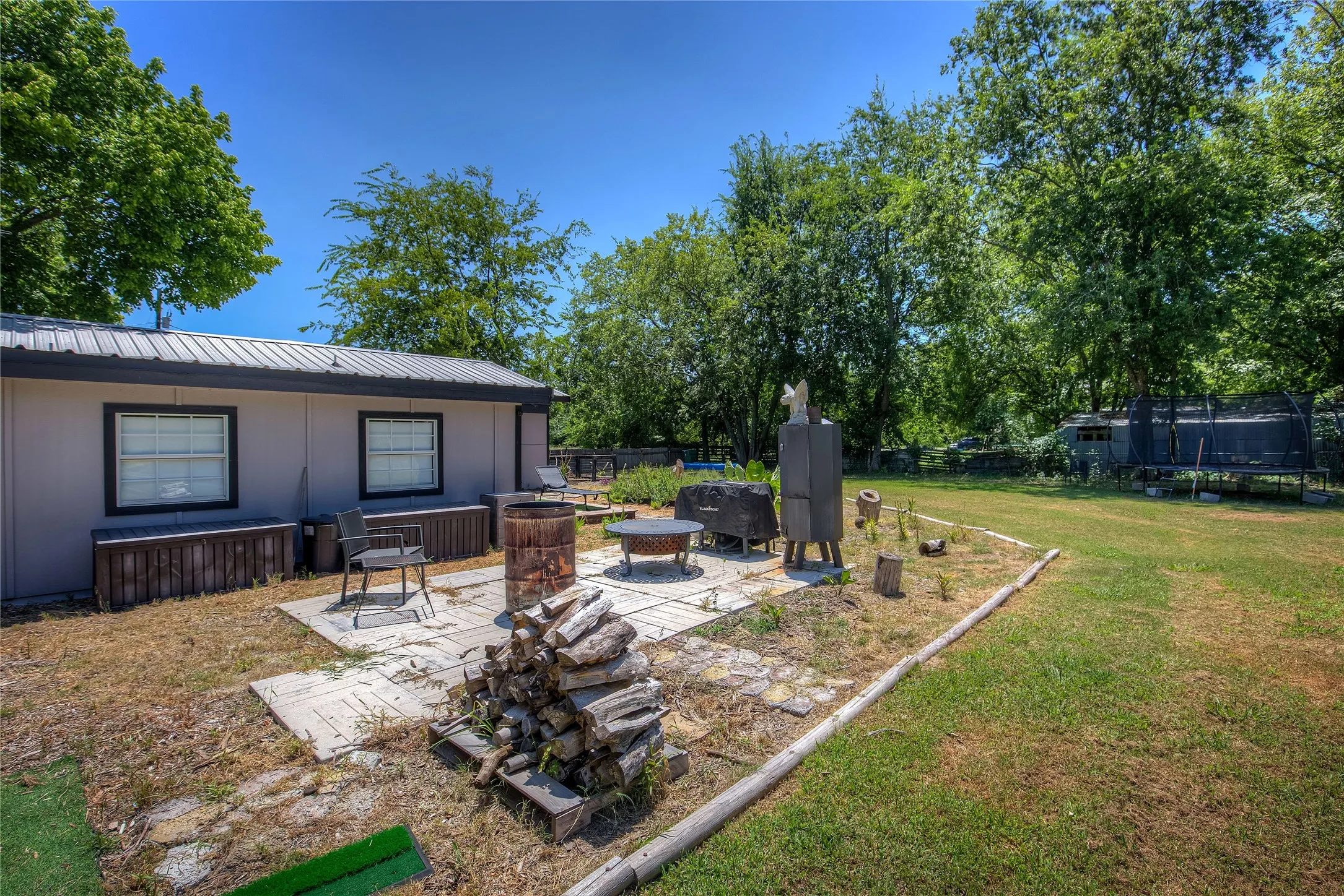 View of yard featuring a trampoline, an outdoor fire pit, and a patio