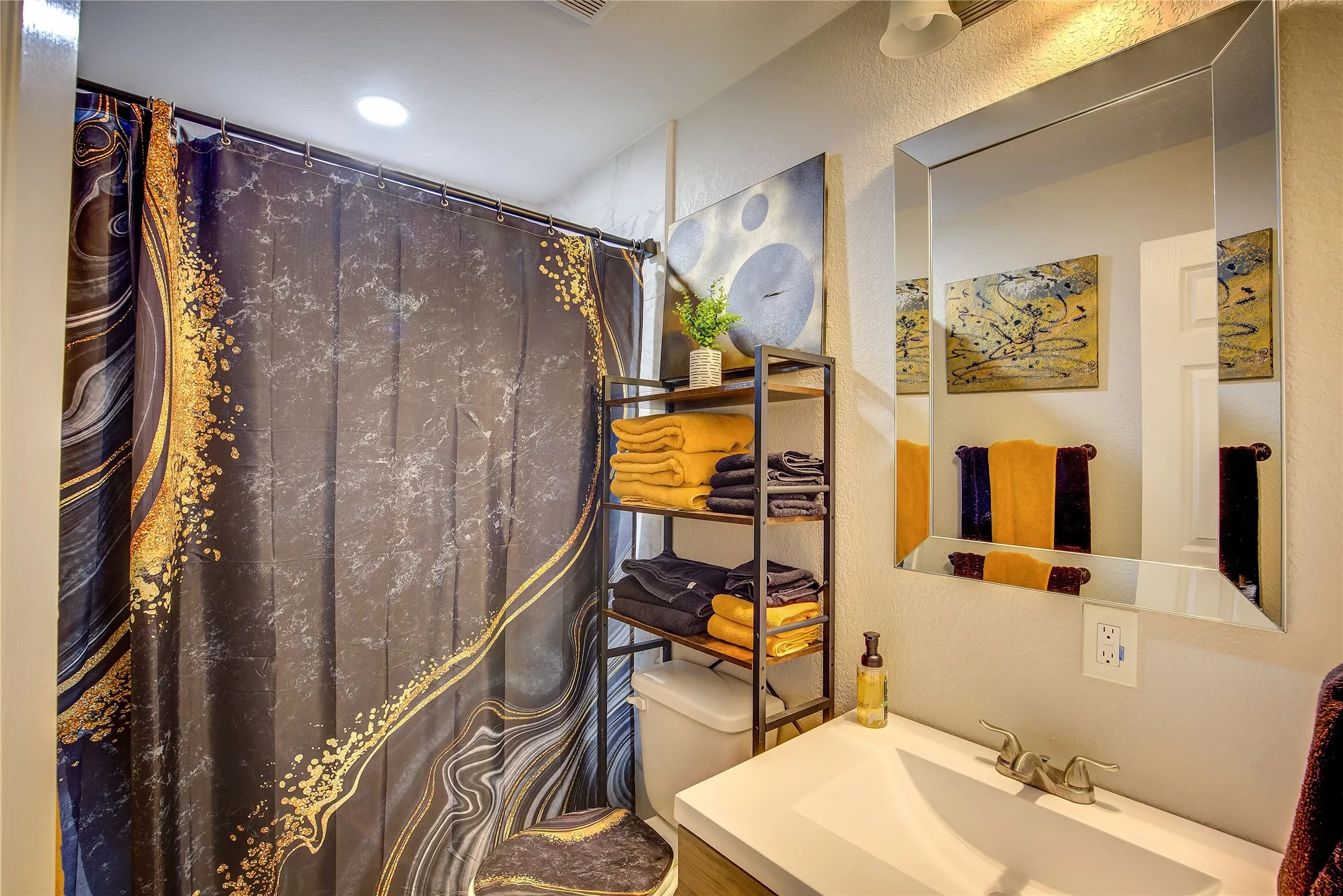 Full bathroom featuring a textured wall, vanity, and a shower with shower curtain