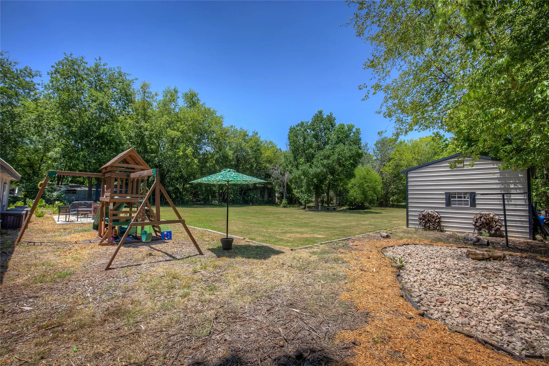 View of green lawn with a playground and an outdoor structure