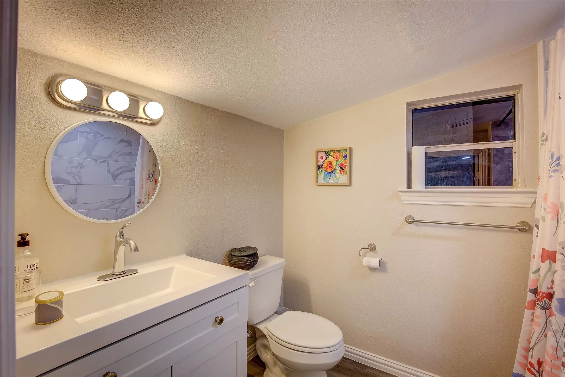 Bathroom featuring a textured ceiling, vaulted ceiling, vanity, wood finished floors, and a textured wall
