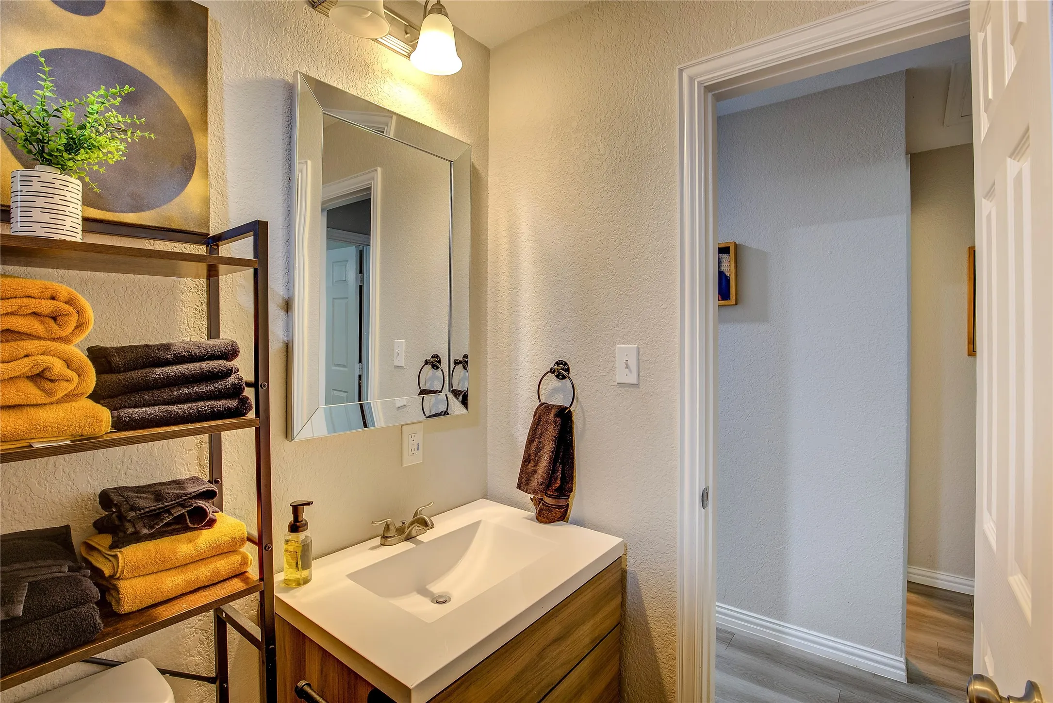 Bathroom with a textured wall, vanity, and wood finished floors