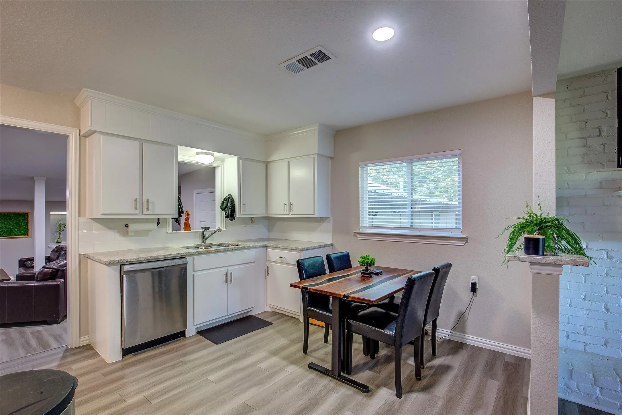 Kitchen featuring light countertops, stainless steel dishwasher, white cabinetry, and light wood-style flooring
