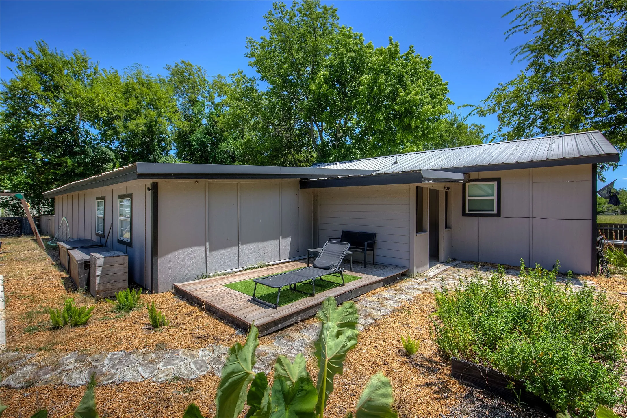 Rear view of property featuring a metal roof and a wooden deck