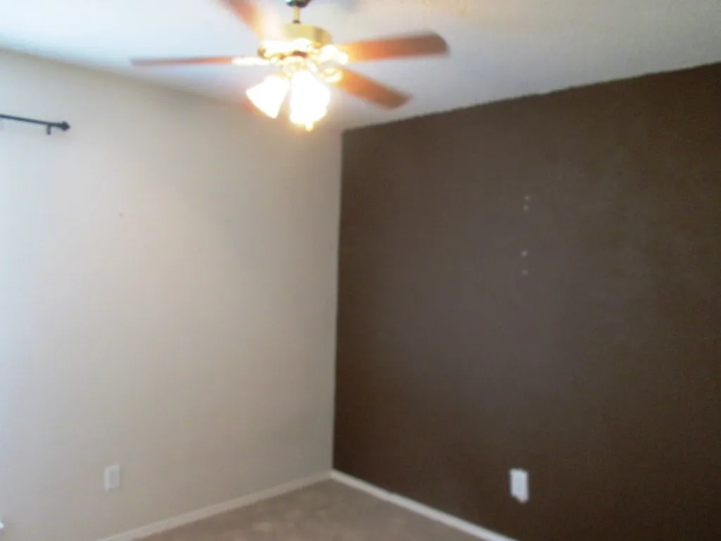 Room featuring a ceiling fan with light fixture, neutral-toned walls, and carpet flooring