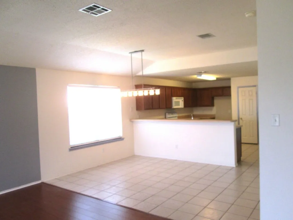 Open-concept living area featuring a kitchen with wood cabinetry, a built-in microwave, and a breakfast bar