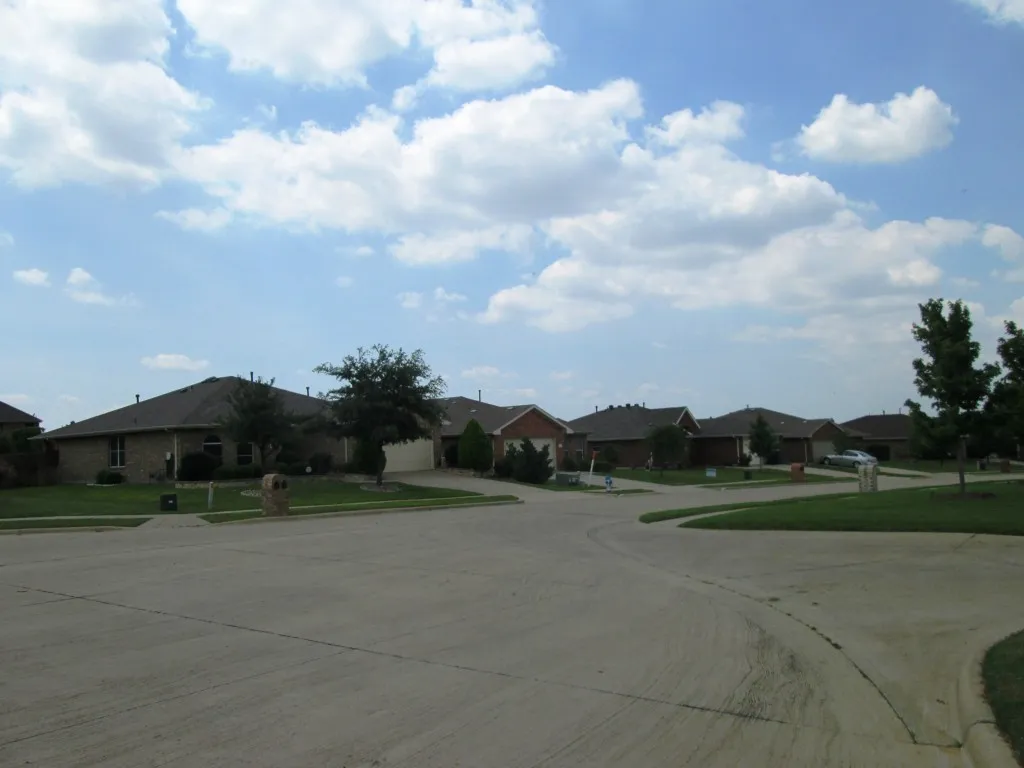 Quiet cul-de-sac street featuring a collection of brick residences with dark shingle roofs