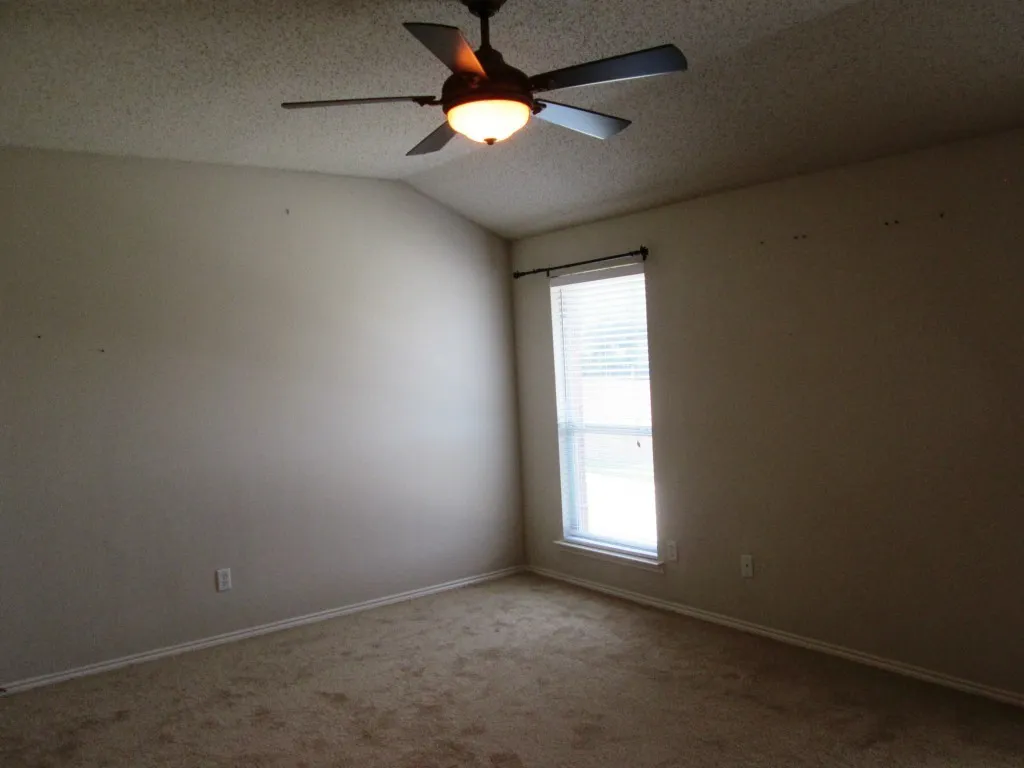 Carpeted room featuring a vaulted ceiling and a ceiling fan with integrated lighting