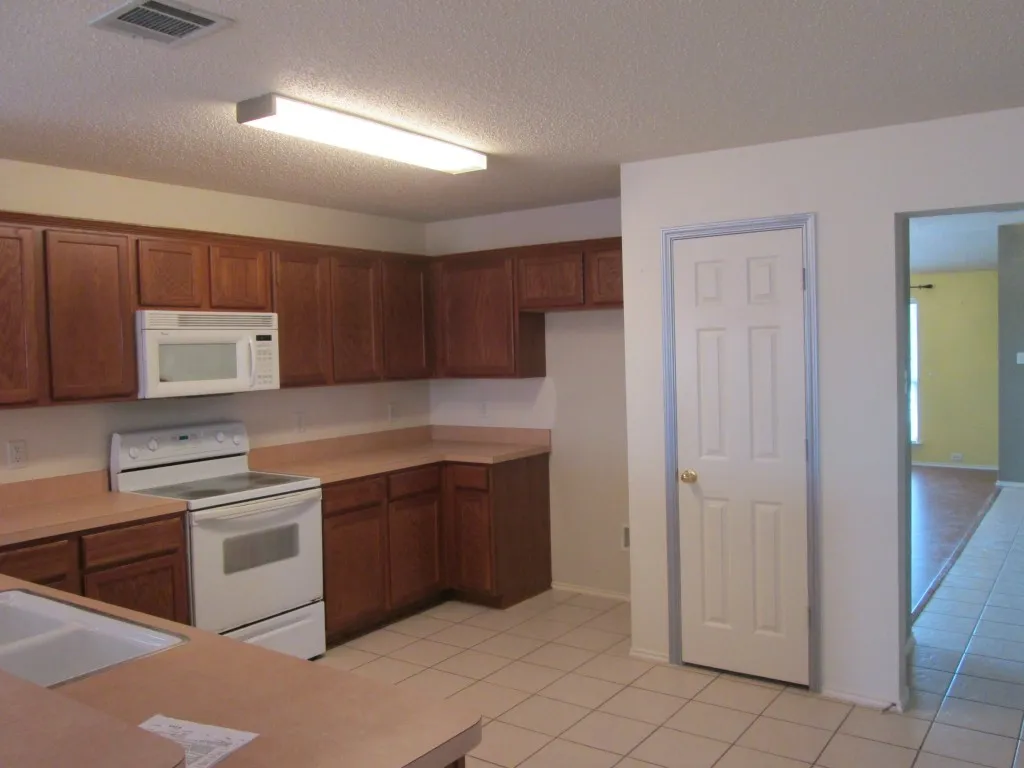 Kitchen featuring wood cabinetry, laminate countertops, a white electric range, and an over-the-range microwave
