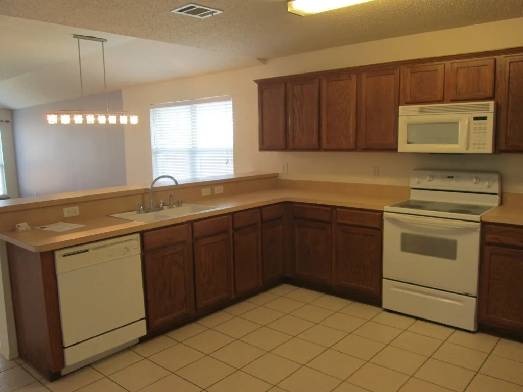 U-shaped kitchen featuring wood cabinetry, laminate countertops, and tile flooring