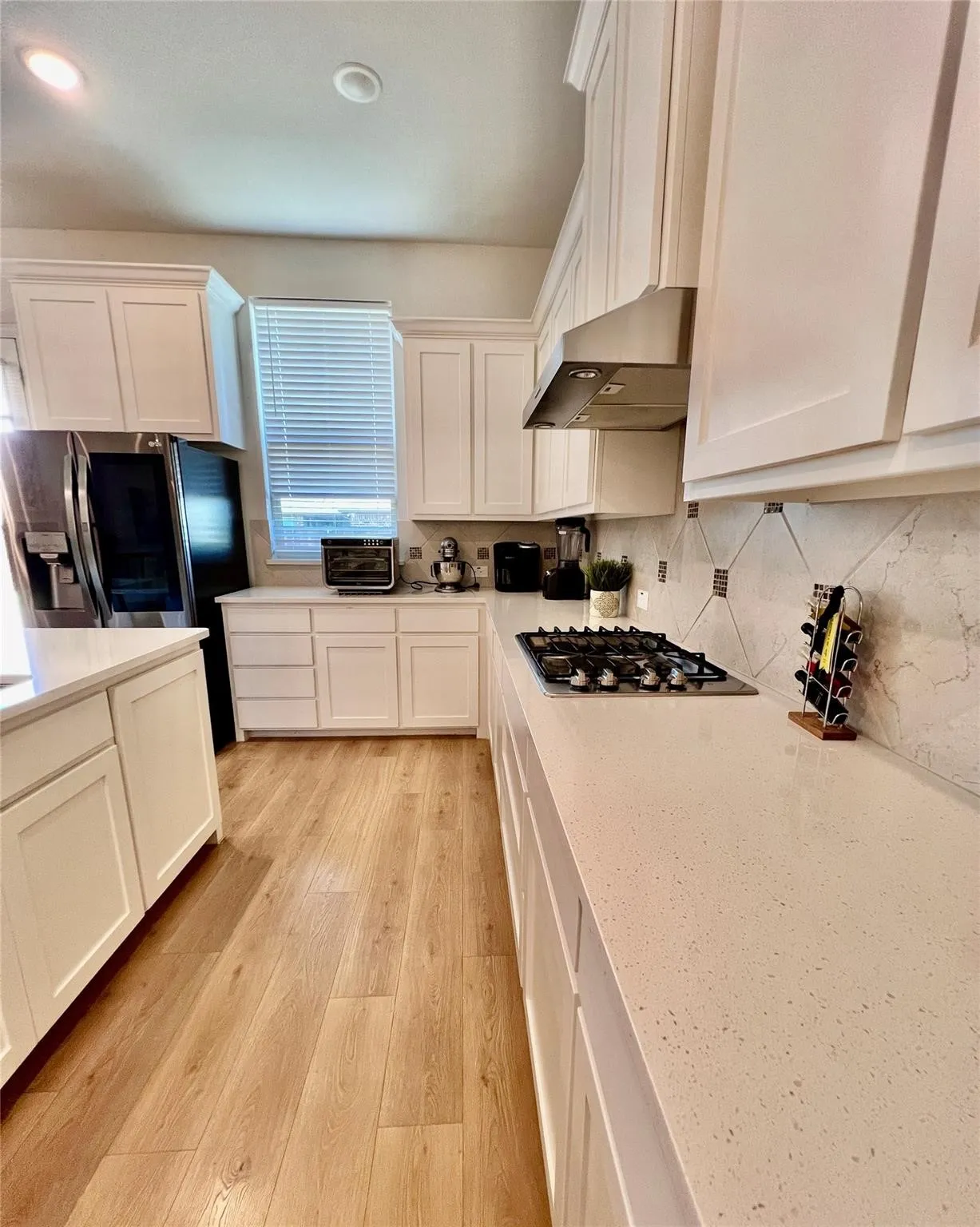 Kitchen featuring light wood-finish flooring, white cabinetry, light-toned countertops, and a gas cooktop