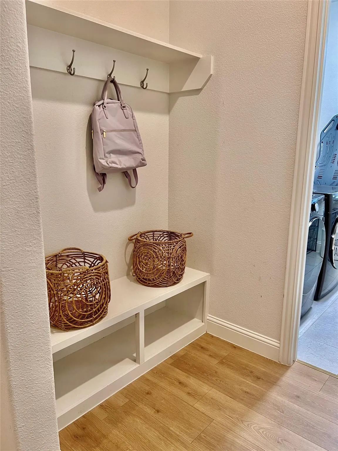 Built-in entryway bench with open storage, integrated coat hooks, and an overhead shelf