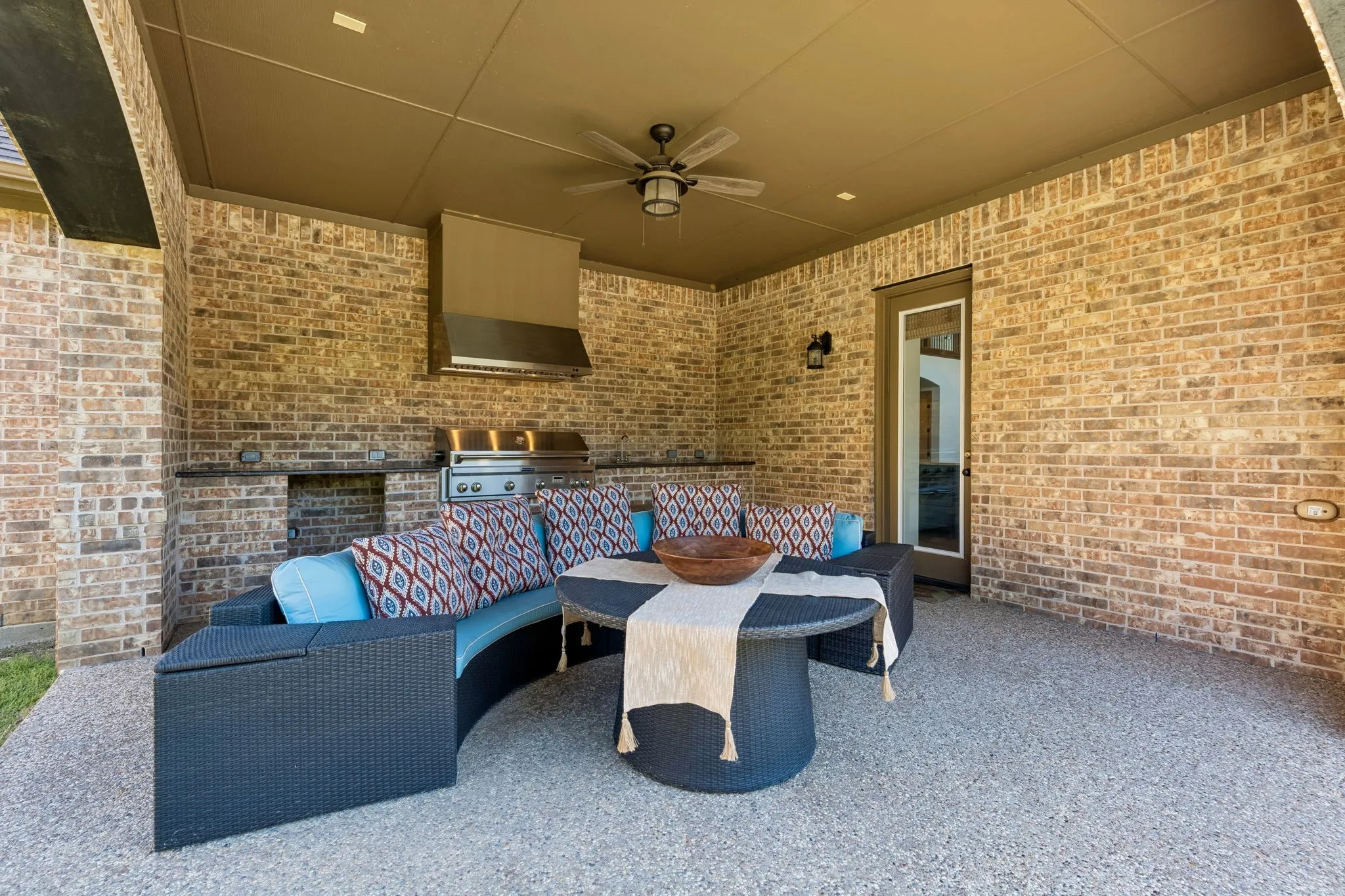 Covered outdoor patio featuring a stainless steel grill and range hood, sink, storage and place for a mini fridge