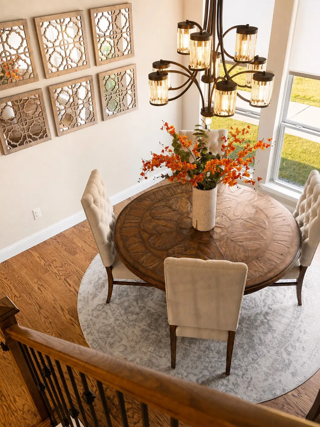 Elegant dining area featuring a carved round table, upholstered chairs, and a chandelier with amber glass shades