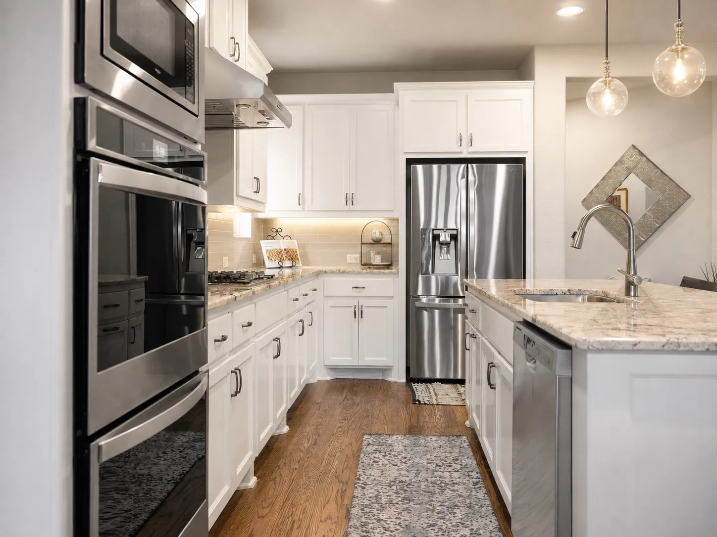 Kitchen featuring wood-finish flooring, white cabinetry, stainless steel appliances, and granite countertops