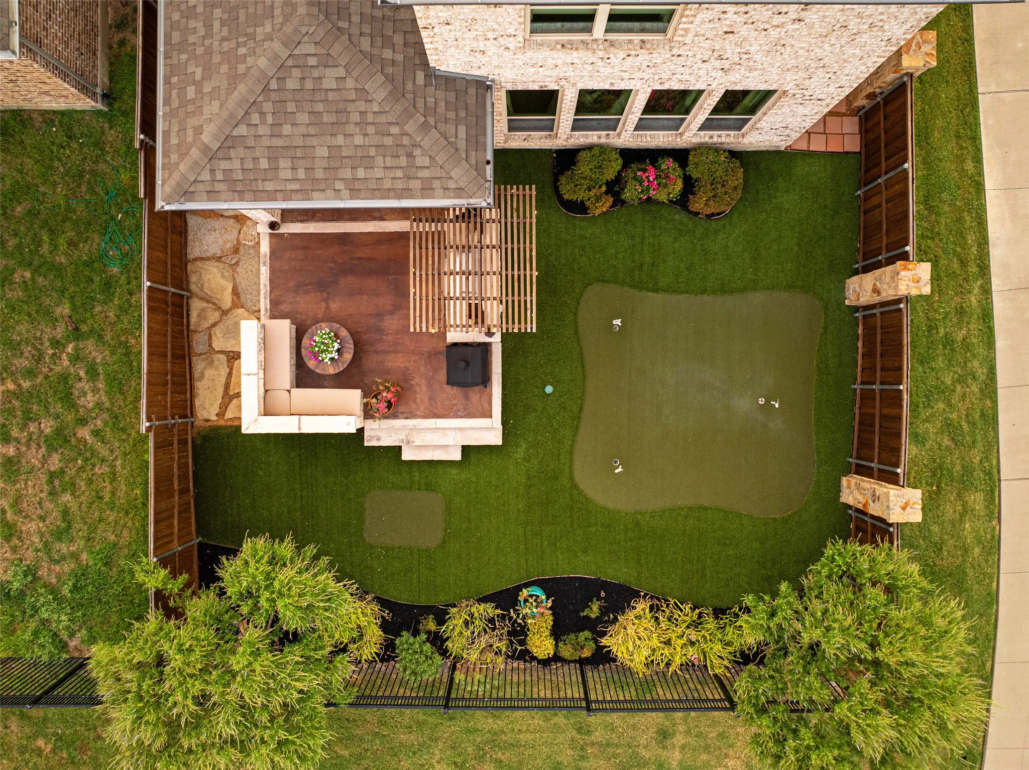 Expansive backyard featuring a built-in putting green, a stone and wood-finish patio, and composite fencing