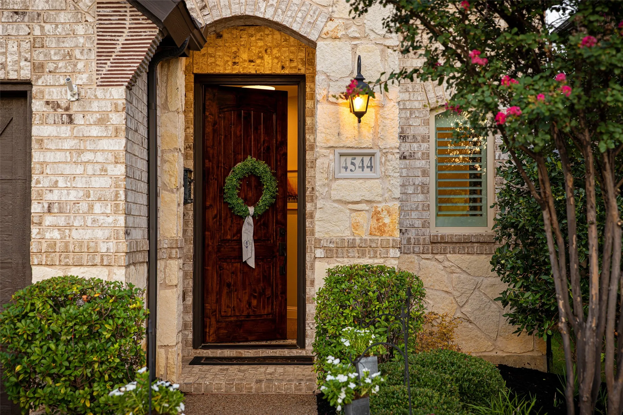 Rich wood-finish front door framed by a stone archway