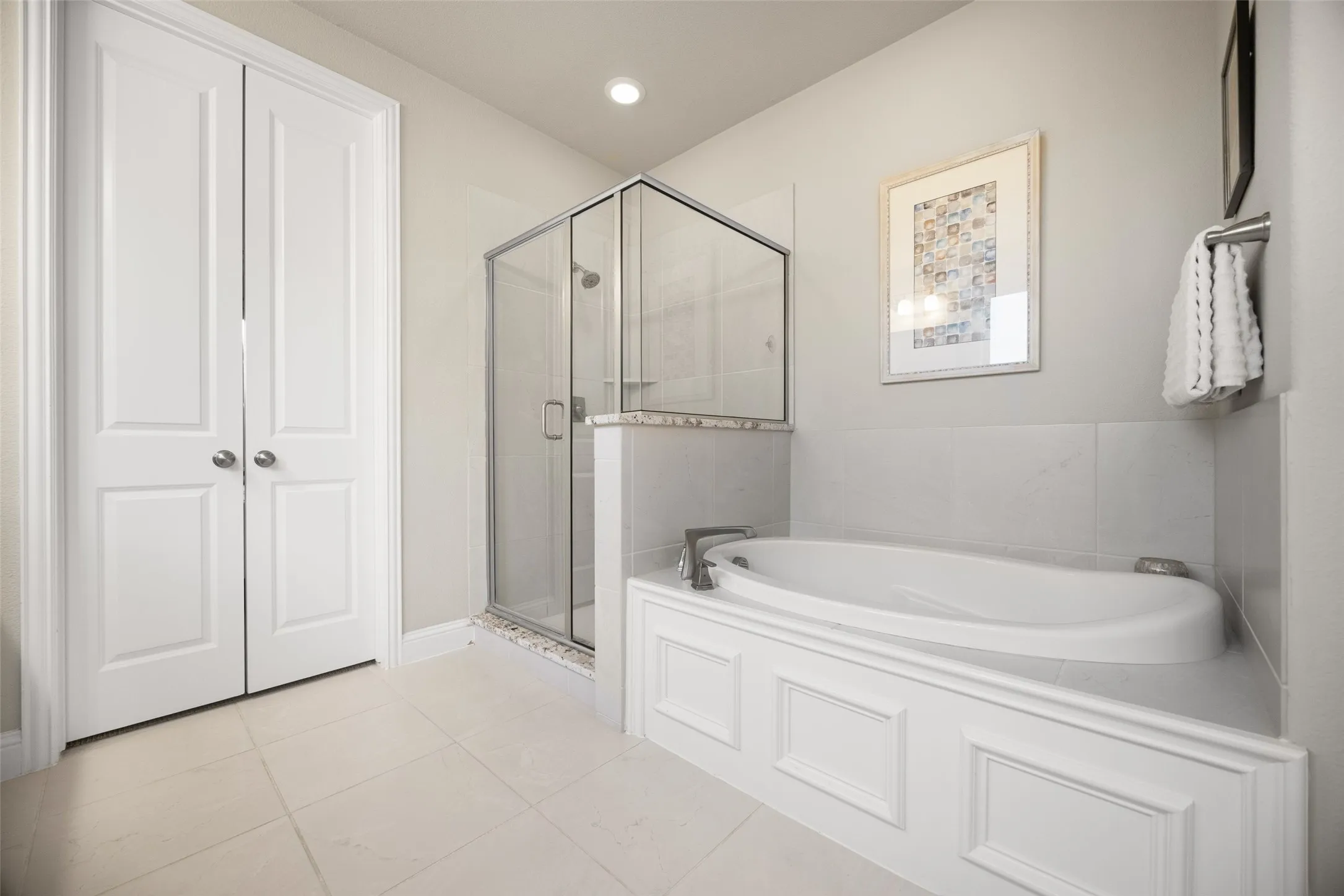 Spacious bathroom featuring a corner soaking tub with paneling, an enclosed glass shower, and light-toned tile flooring