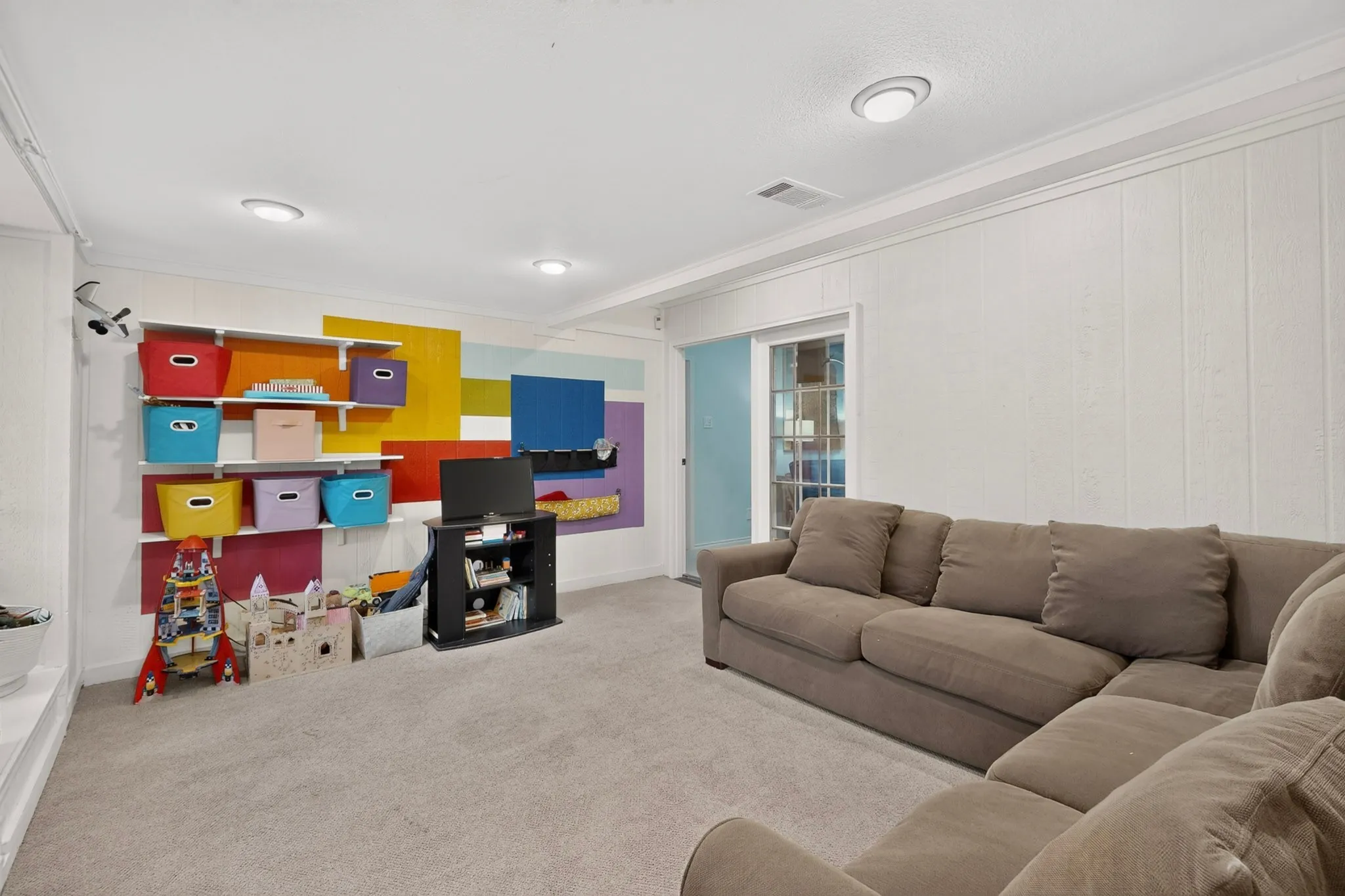 Spacious interior room featuring light-colored carpeting and white paneled walls