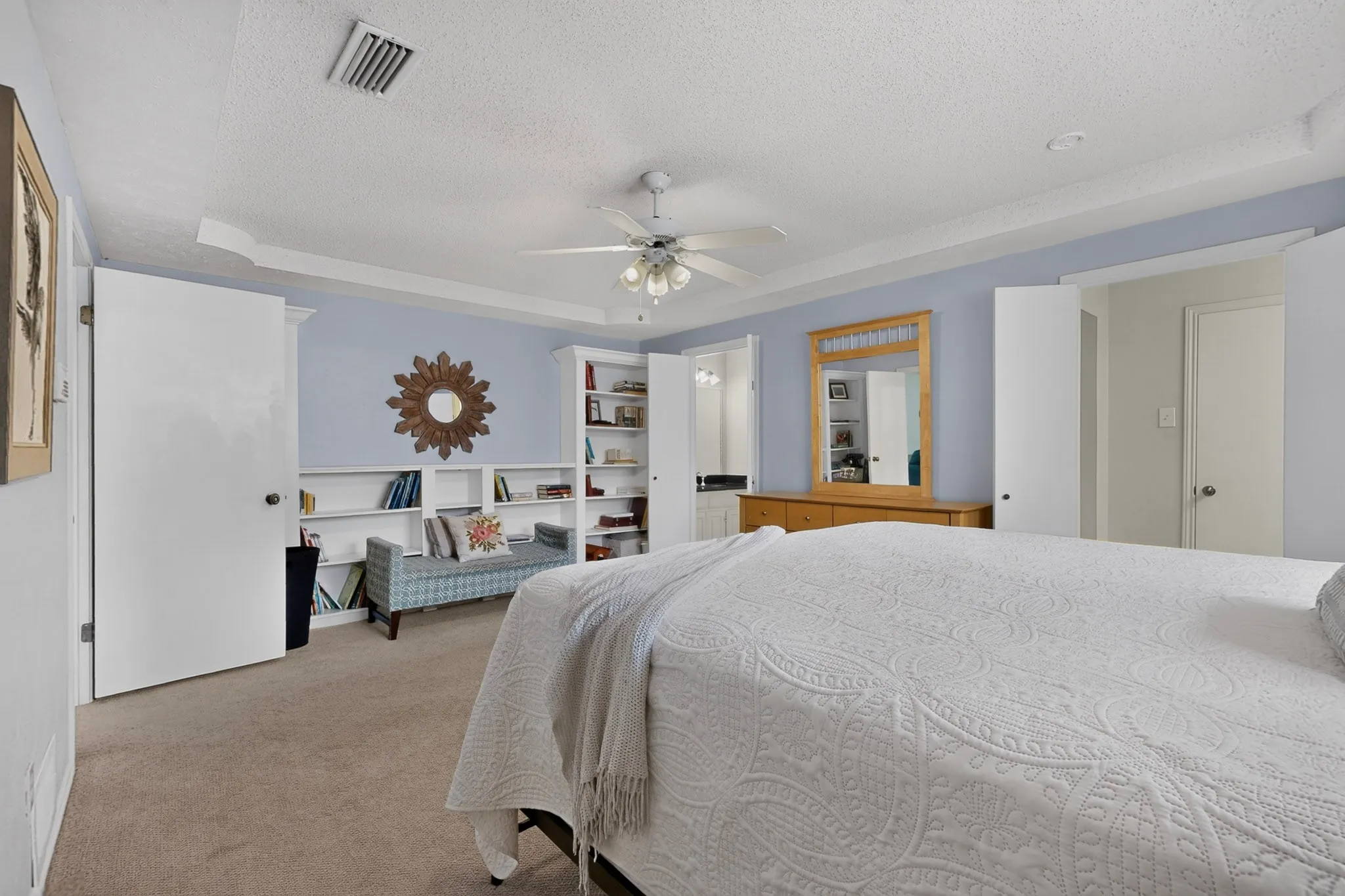 Bedroom featuring built-in shelving, tray ceiling, ceiling fan, and carpeted flooring
