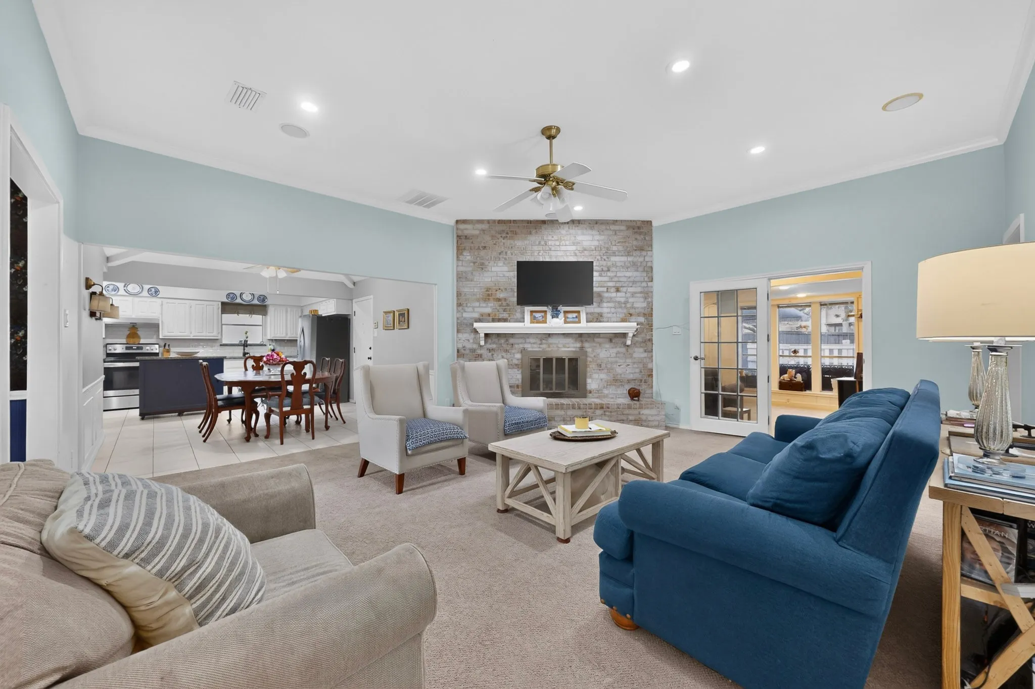 Spacious living area featuring a brick-clad fireplace with a white mantel, recessed lighting, and crown molding