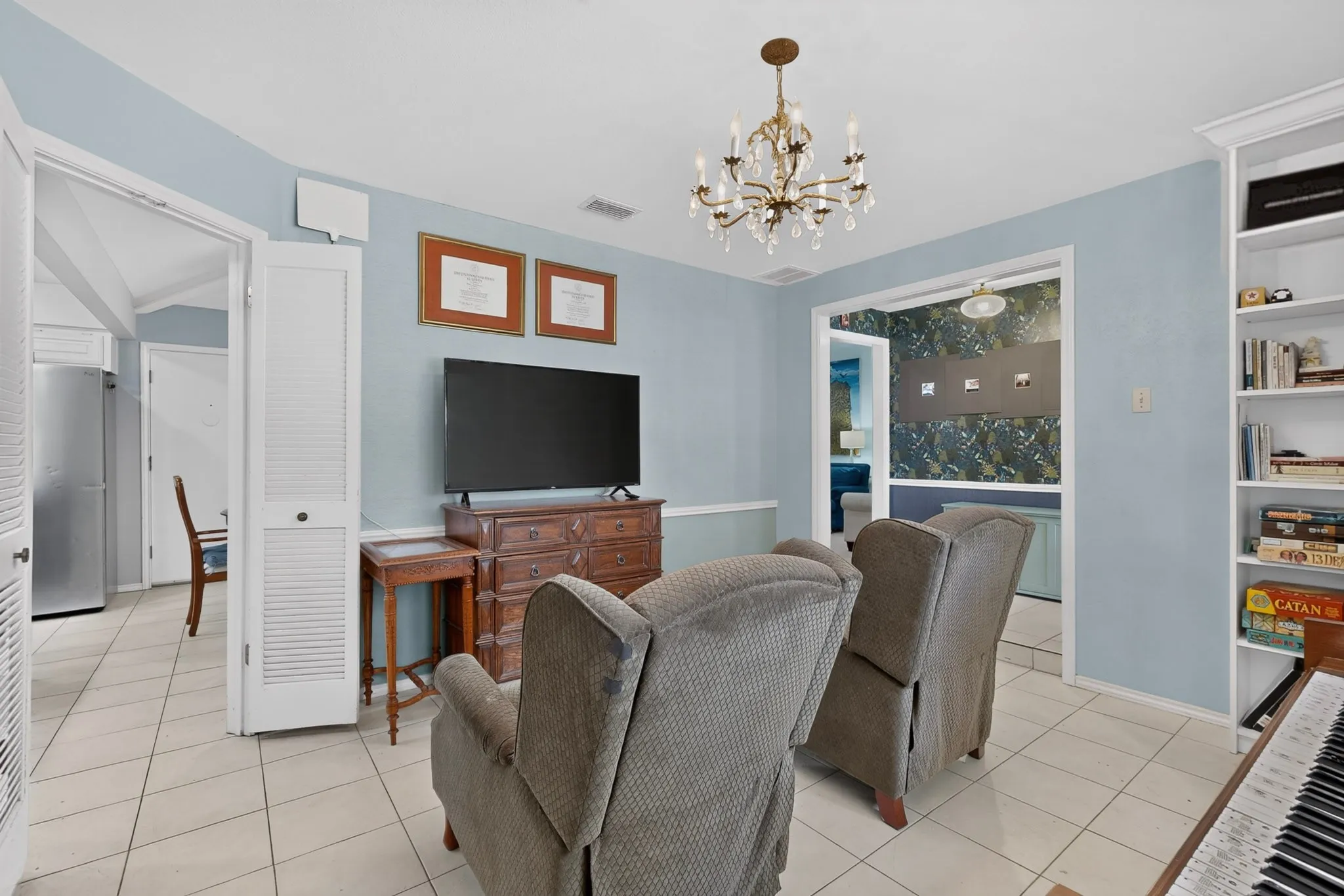 Living area featuring tile flooring, a decorative chandelier, and a built-in shelving unit