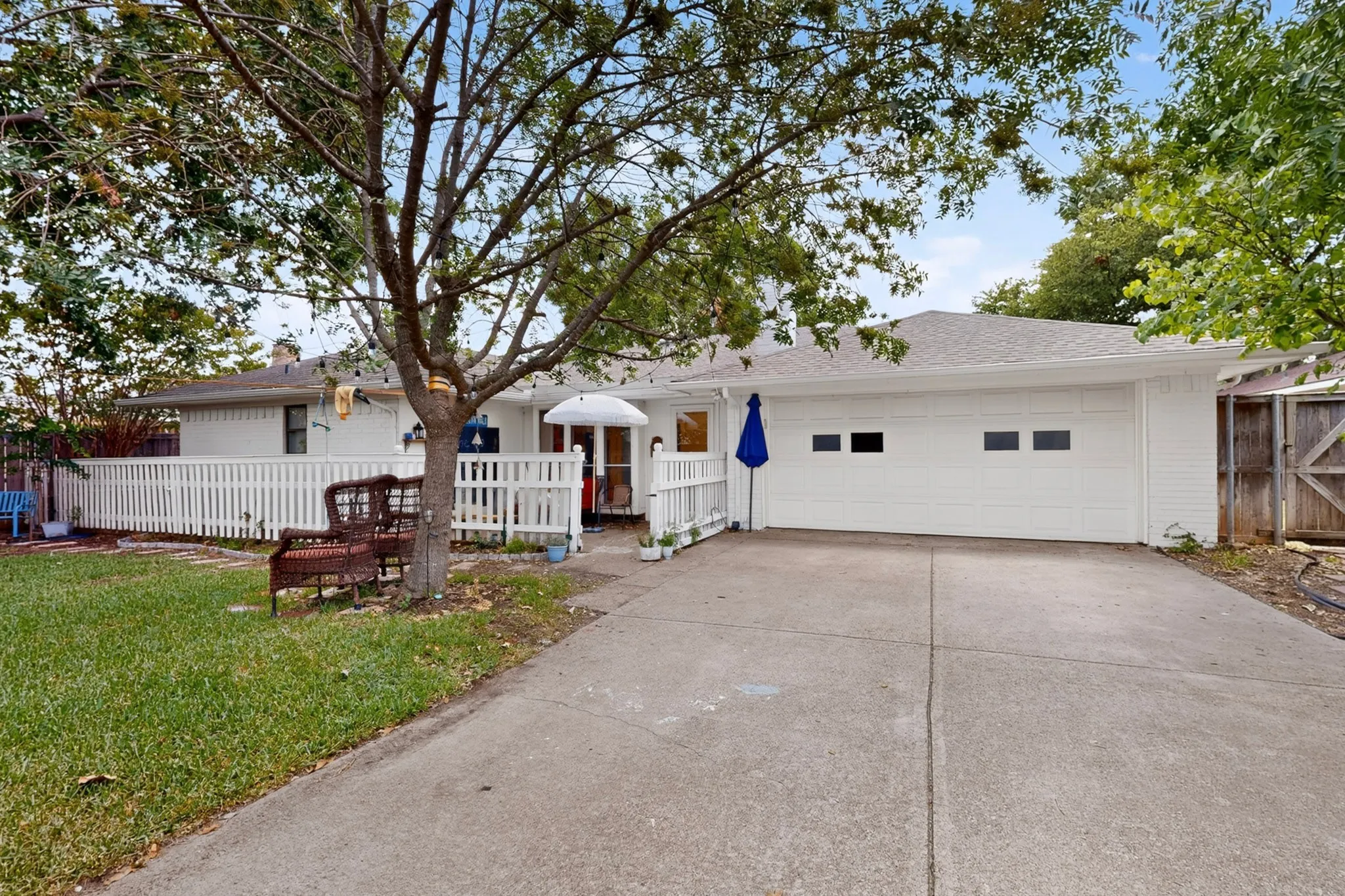 White picket fence enclosing a paved patio and Dog run area