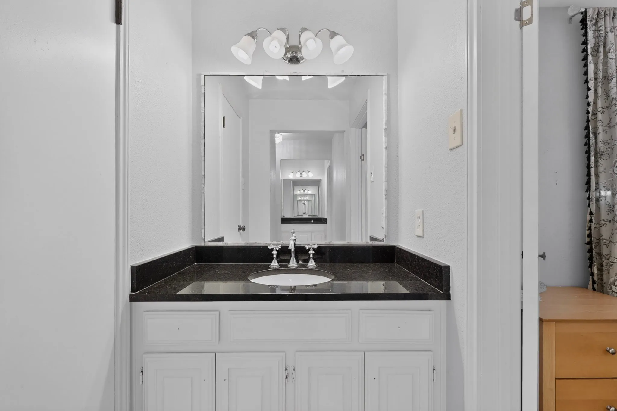 Bathroom vanity matching on the opposite of the bathroom with a dark countertop and undermount sink