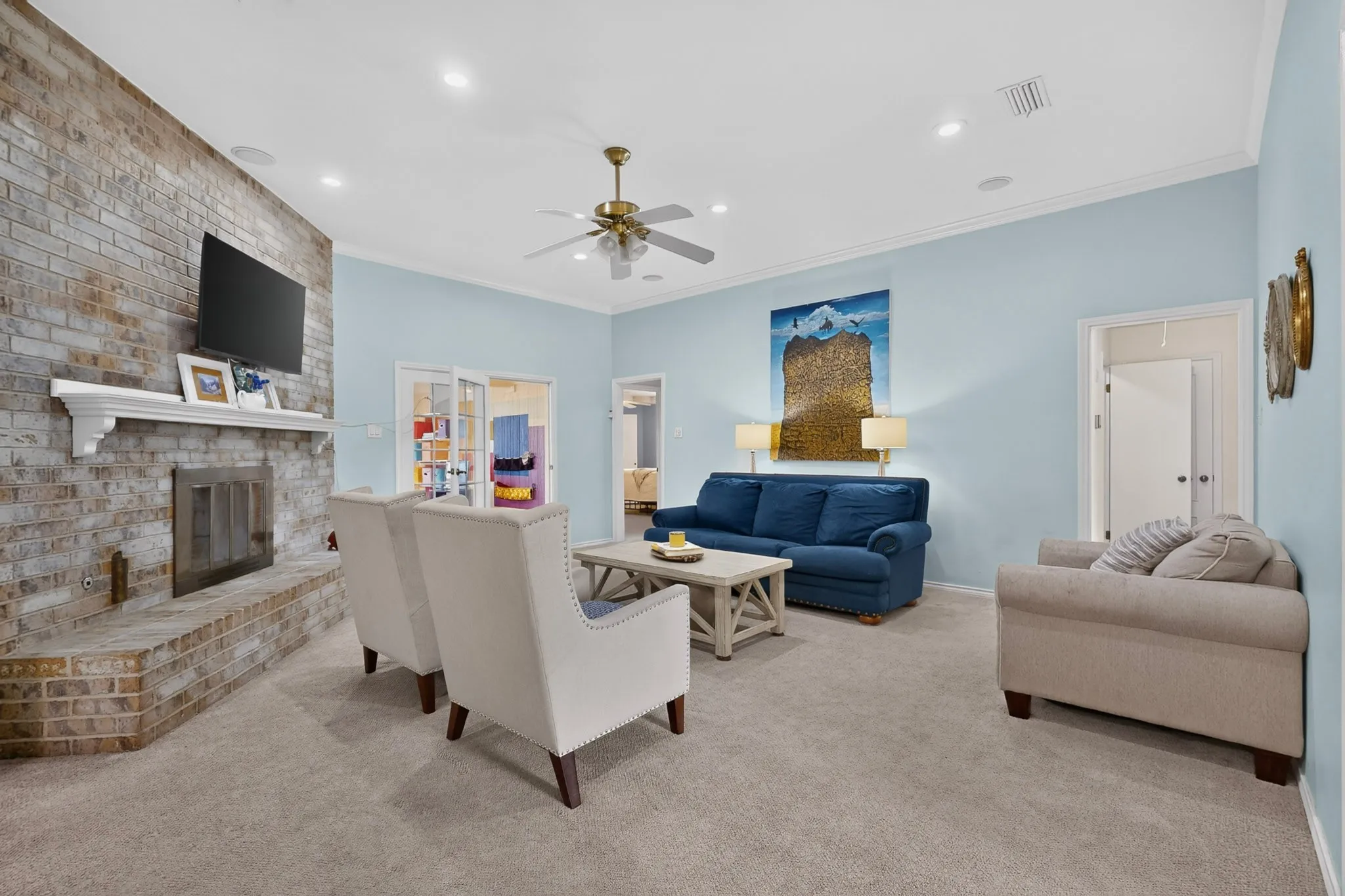 Spacious living area featuring a brick fireplace with a white mantel, recessed lighting, and crown molding