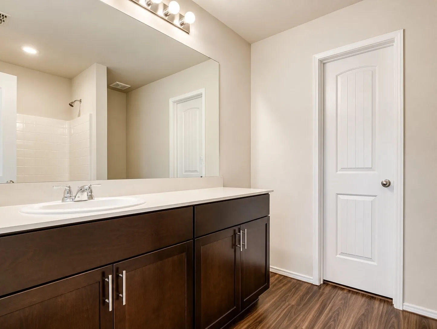 Bathroom vanity featuring dark wood-finish cabinetry, a white countertop, and an integrated sink with a chrome faucet