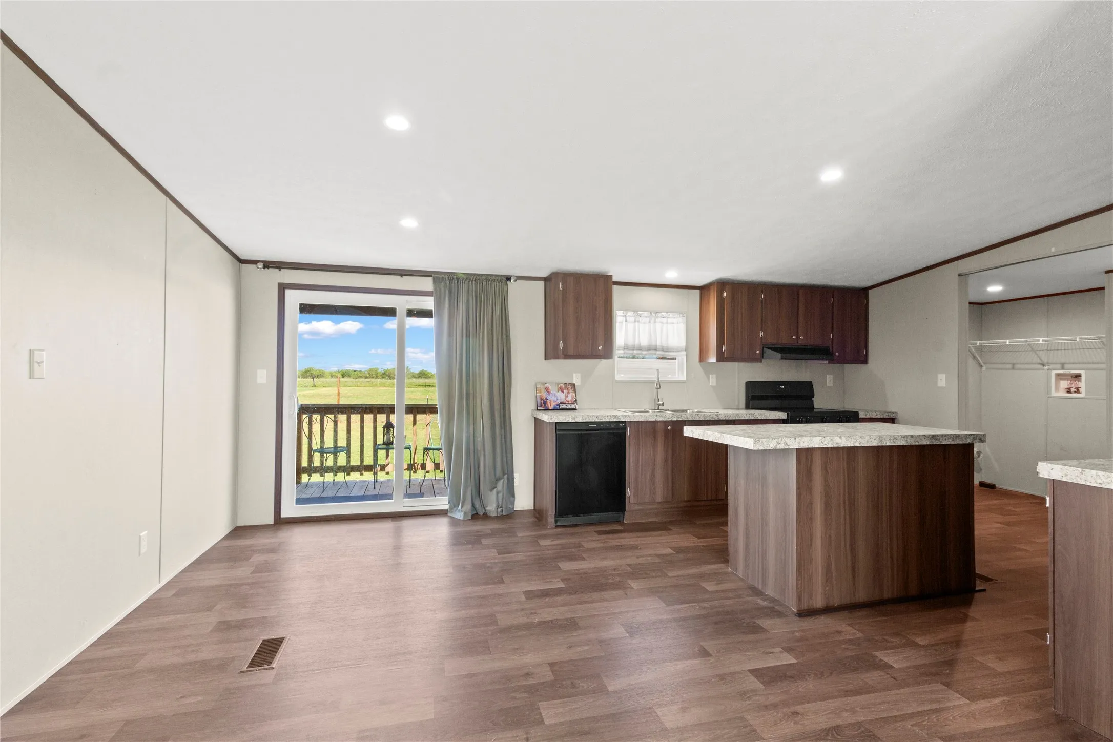 Open-concept living area featuring wood-finish flooring, recessed lighting, and a sliding glass door to an exterior deck