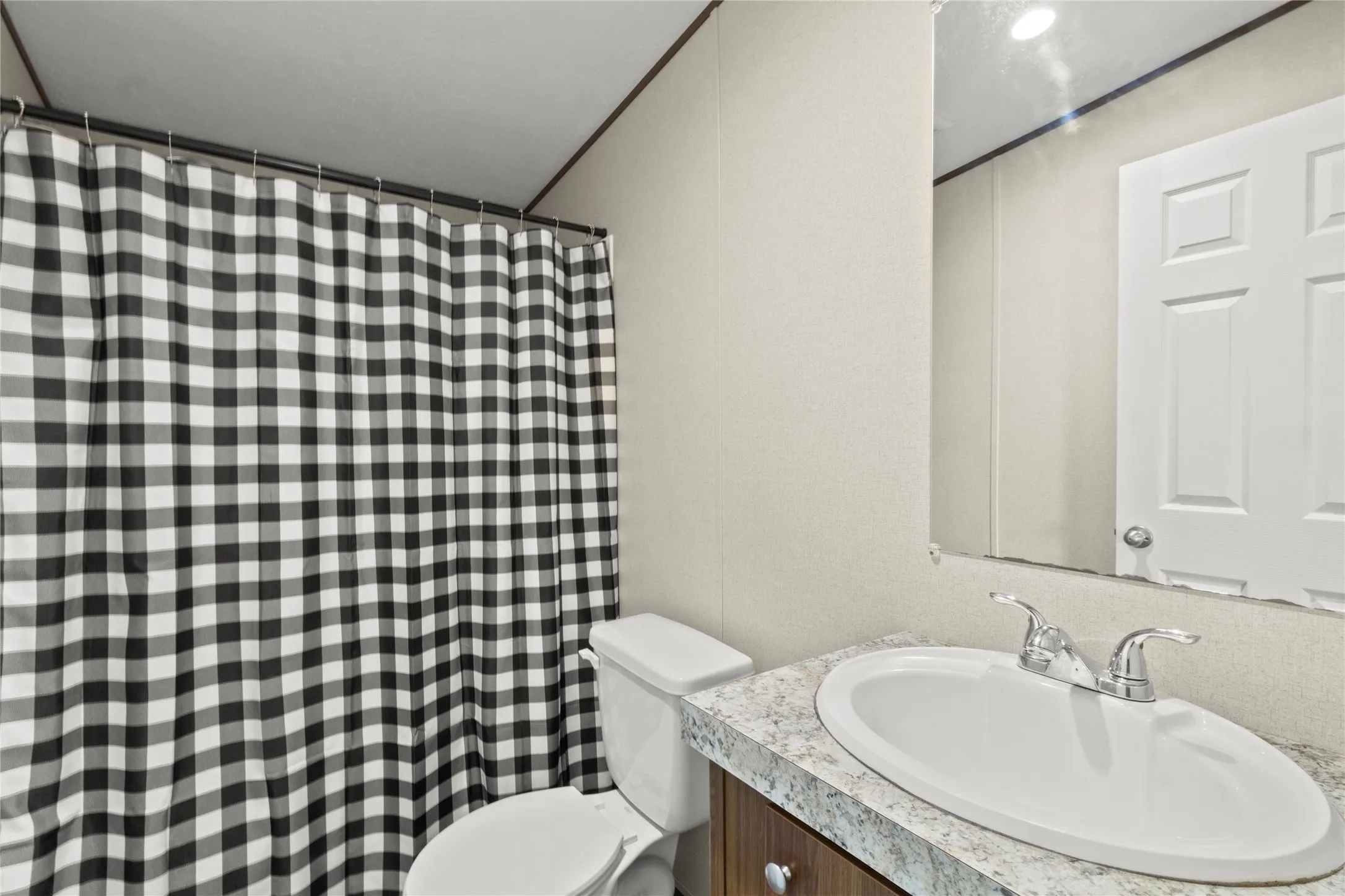 Bathroom featuring a white toilet, an integrated sink with a chrome faucet, and a vanity with a light-colored countertop