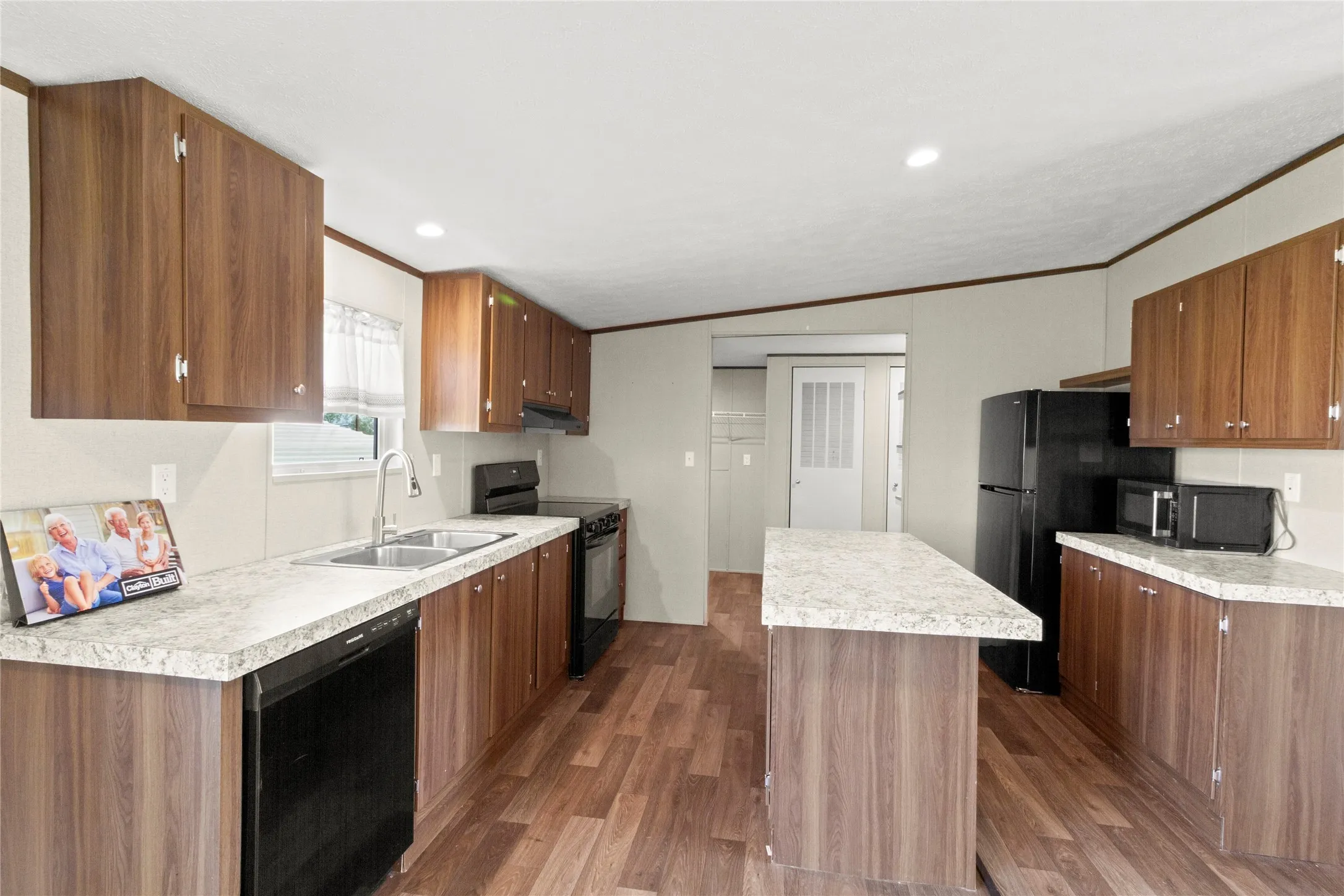 Expansive kitchen featuring wood-finish cabinetry, light-toned countertops, and wood-finish flooring
