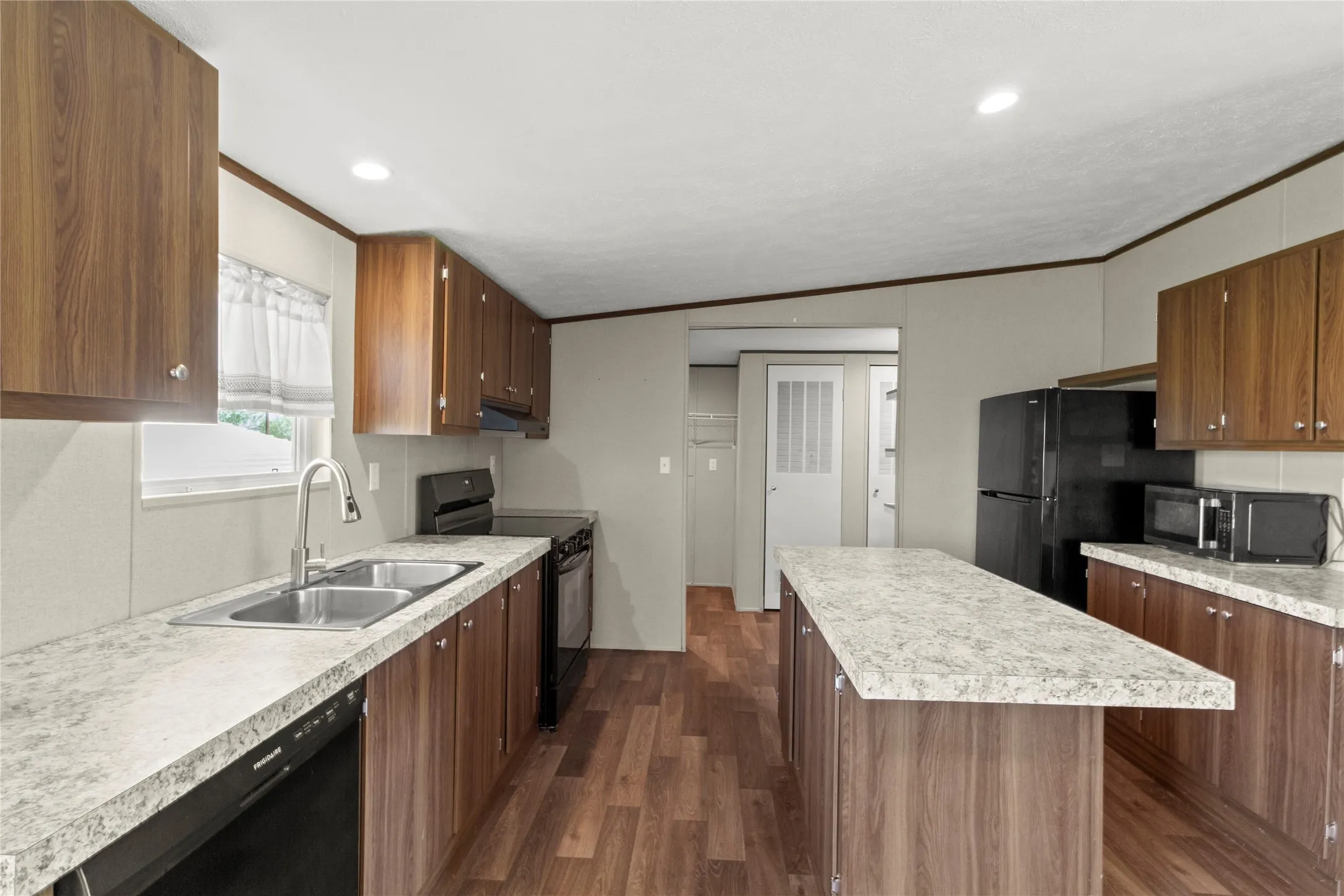 Kitchen featuring wood-finish cabinetry, light-toned countertops, and wood-finish flooring