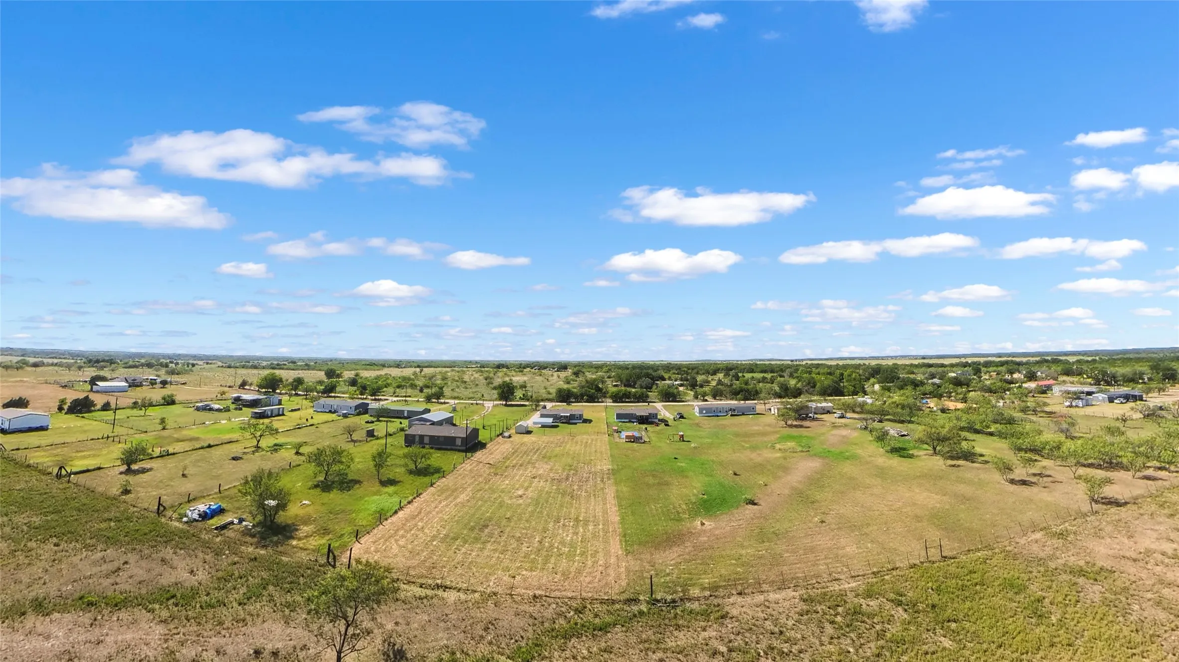 Expansive rural landscape featuring a mix of cultivated fields and open grassy areas