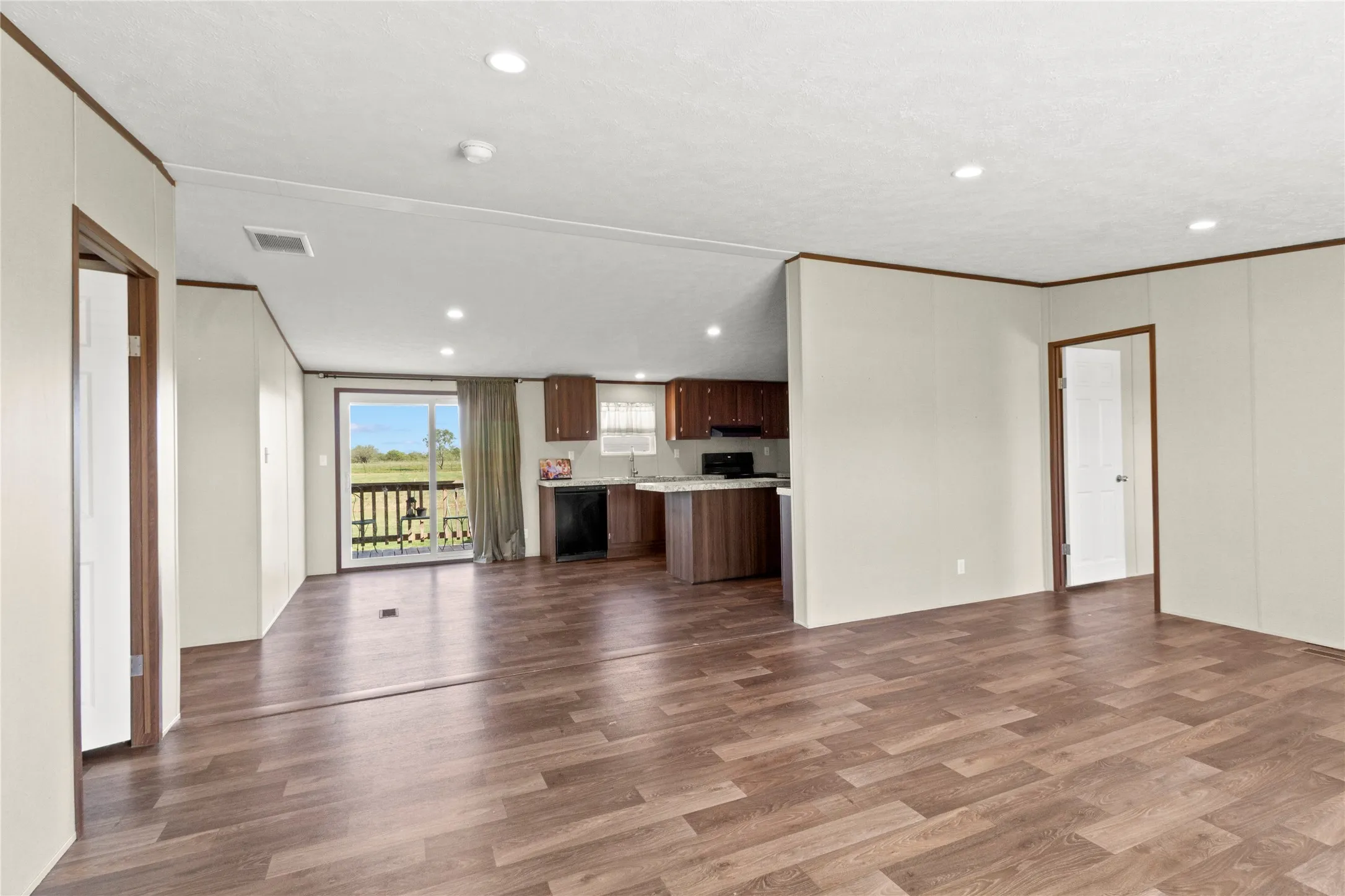 Open-concept living space featuring wood-finish flooring, recessed lighting, and a sliding glass door