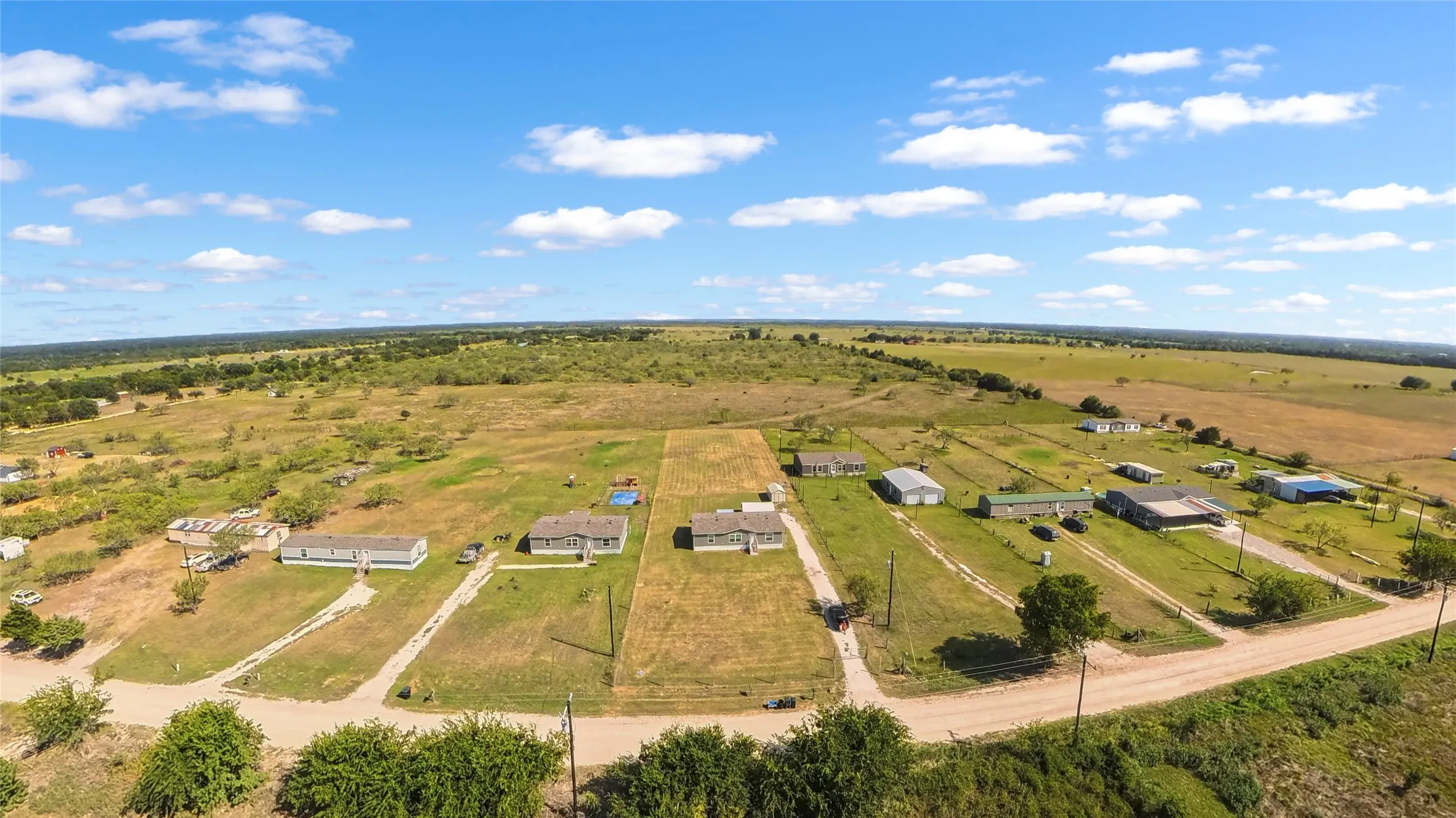 Expansive aerial landscape featuring multiple residential structures and open land